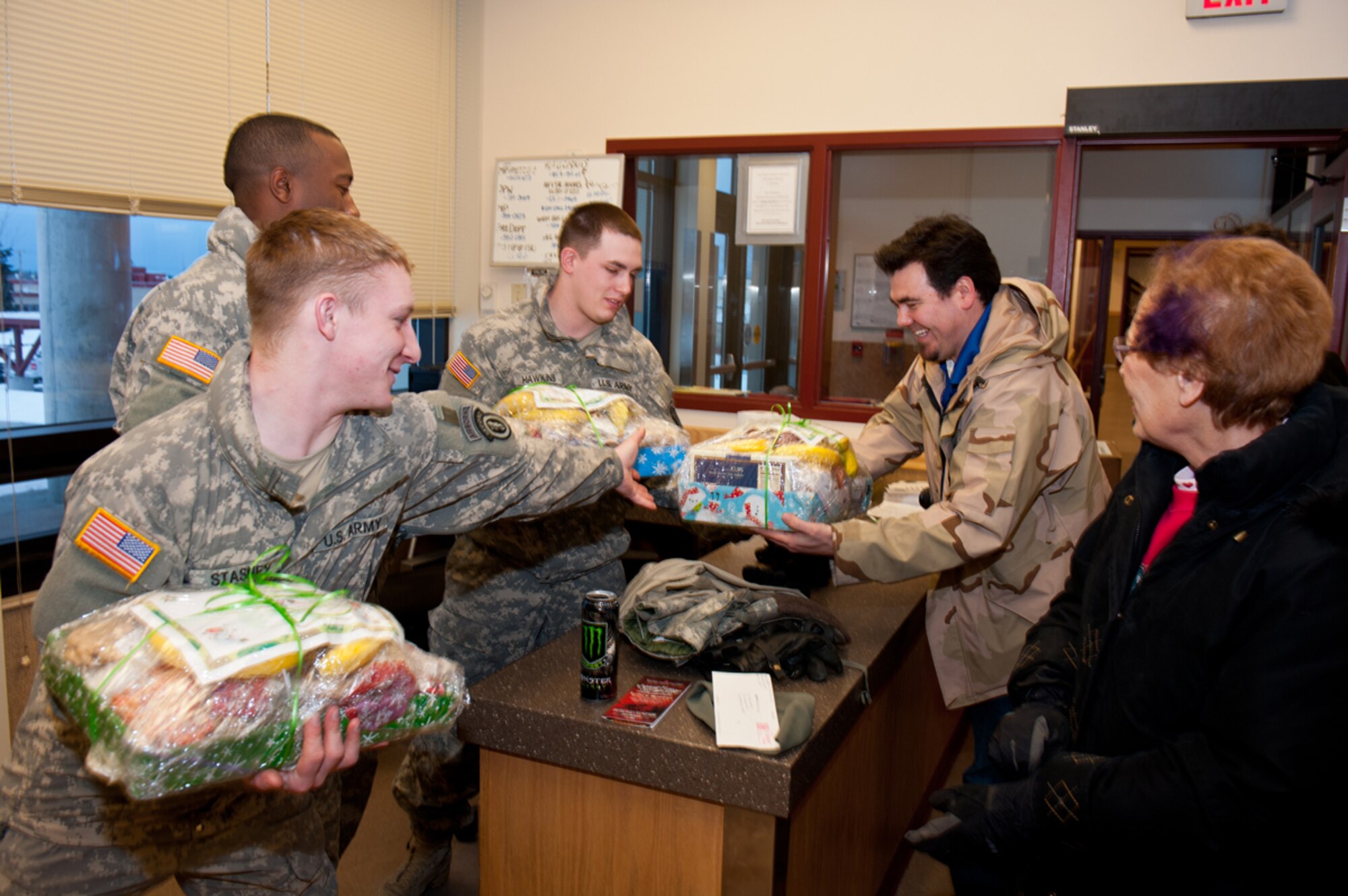 JOINT BASE ELMENDORF-RICHARDSON, Alaska -- From left, Spc. William Stasney, Sgt. Xaviar Green, and Pvt. Adam Hawkins, all of the 84th Expeditionary Support Company (Airborne), 6th Engineer Battalion, reach for one more holiday platter filled with cookies and fruit, from Rob German, Marketing Director for the Armed Services YMCA, and Bonnie Berger, volunteer, Dec. 20. (U.S. Air Force photo/Johnathon Green)
