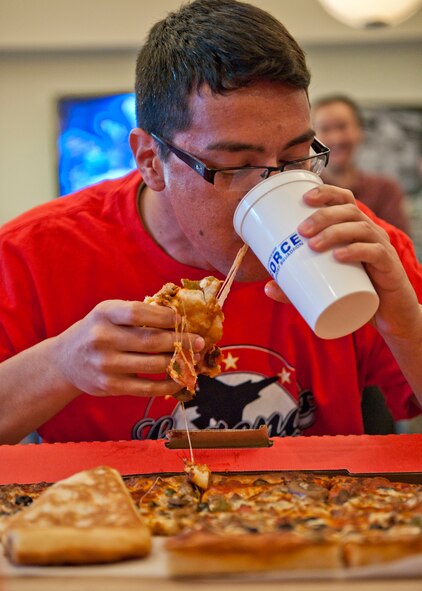 Jason McWilliams, of the 96th Security Forces Squadron, combines some cheese with his gulp of water during a pizza-eating contest at Legends Sports Grill Jan. 5 at Eglin Air Force Base, Fla.  The team competition of devouring three large pizzas in 10 minutes or less was part of the official grand opening of Legends Sports Grill, a new restaurant at Eglin’s old enlisted club.  SFS beat out four other teams, finishing off their pizzas in under eight minutes.  (U.S. Air Force photo/Samuel King Jr.)