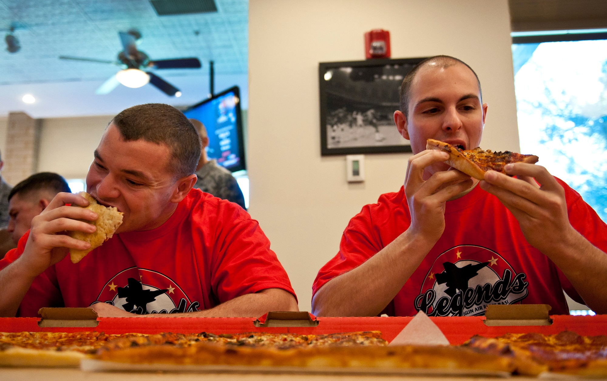 Brandon Lugo and Patrick Barbarino, from the 46th Test Wing, try to scarf down three large pizzas in 10 minutes as the pizza-eating contest’s only two-person team, Jan. 5 at Eglin Air Force Base, Fla.  The contest was part of the official grand opening of Legends Sports Grill, a new restaurant at Eglin’s old enlisted club.  The 96th Security Forces Squadron team beat out four other teams, finishing off their pizzas in under eight minutes.  (U.S. Air Force photo/Samuel King Jr.)