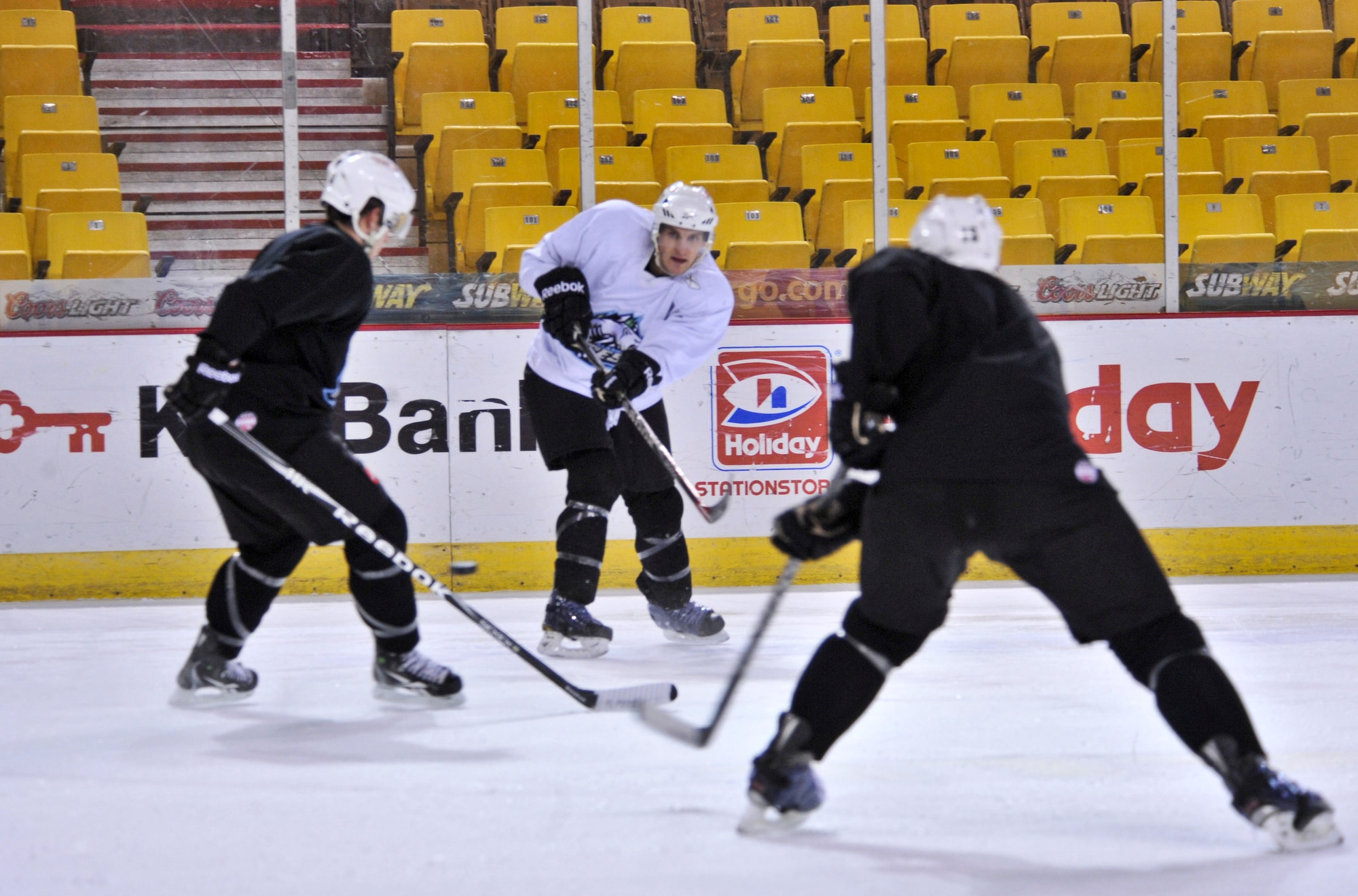 ANCHORAGE, Alaska  –  Jacques Lamoureux, middle, left wing for the Alaska Aces, shoots the puck between two defenders during a practice at the Sullivan Arena Dec. 28. Lamoureaux not only plays professional hockey with the Aces, he’s also a second lieutenant assigned to the 673d Contracting Squadron at Joint Base Elmendorf-Richardson. (U.S. Air Force photo/Senior Airman Christopher Gross)