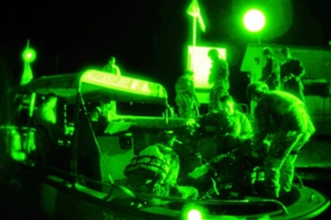 As seen through a night-vision device, the U.S. Coast Guard Maritime Safety and Security Team San Diego and the U.S. Marine Corps Security Forces Company simulate the egress of injured people onto a Coast Guard fast boat during an evacuation exercise in Guantanamo Bay, Cuba, Dec. 30, 2011.