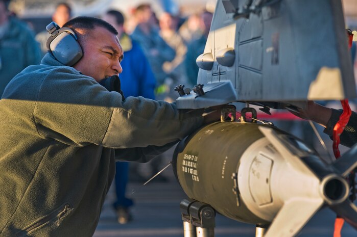 U.S. Air Force Staff Sgt. Hector Miranda, 57th Aircraft Maintenance Squadron aircraft armament systems craftsman, tightens the bolts to secure a Mark-82 bomb to a F-16 Fighting Falcon during the quarterly weapons load competition Jan. 6, 2012, at Nellis Air Force Base, Nev. Weapons load competitions are conducted quarterly to keep Airmen sharp and recognize superior performers. Weapons load teams are evaluated for use of the checklist, safety, and overall speed. (U.S. Air Force photo by Staff Sgt. William P.Coleman/Released)  