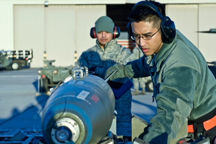 U.S Air Force Staff Sgt. Jason Spears, 57th Aircraft Maintenance Squadron, weapons load crew chief prepares to load a Mark-82 bomb on an F-16 Fighting Falcon while an evaluator watches during the quarterly weapons load competition Jan. 6, 2012, at Nellis Air Force Base, Nev. Weapons load competitions are conducted quarterly to keep Airmen sharp and recognize superior performers. Weapons load teams are evaluated for use of the checklist, safety, and overall speed.  (U.S. Air Force photo by Airman 1st Class Matthew Lancaster/Released)