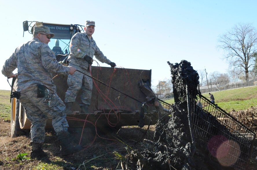 Members of Team Barksdale pull a shopping cart out of a levee which runs along the north perimeter of Barksdale Air Force Base, La., Jan. 3. The Airmen tied up the cart and attached it to a bulldozer in order to pull it out of the muck. Debris gets occasionally washed into the levee due to heavy rains and flooding. The levees are cleaned annually when water levels are low and the debris is visible. (U.S. Air Force photo/Airman 1st Class Andrea F. Liechti)(RELEASED)