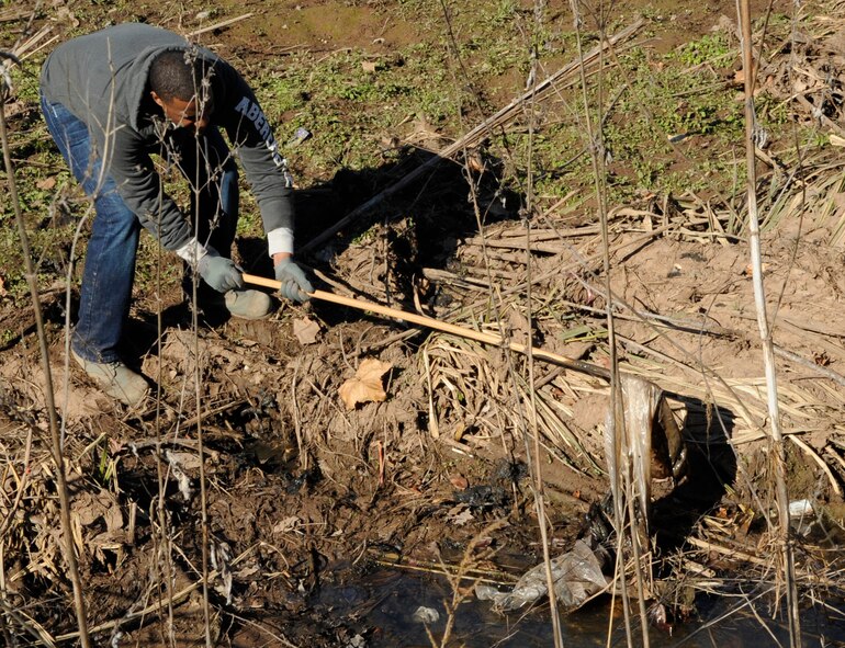 A member of Team Barksdale uses a broom handle to pull trash out of a levee which runs along the north perimeter of Barksdale Air Force Base, La., Jan. 3. Several squadrons came together to make sure Barksdale looks its finest for the Installation Excellence Award Team's arrival Jan. 9. Debris gets occasionally washed into the levee due to heavy rains and flooding. The levees are cleaned annually when water levels are low and the debris is visible. (U.S. Air Force photo/Airman 1st Class Andrea F. Liechti)(RELEASED)