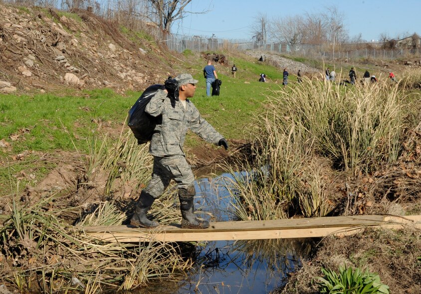 A member of Team Barksdale uses a small bridge to carry trash over water in a levee which runs along the north perimeter of Barksdale Air Force Base, La., Jan. 3. The bridge was built to give the volunteers easy access to both sides of the levee as they picked up trash in preparation for the Installation Excellence Award Team's arrival Jan. 9. Debris gets occasionally washed into the levee due to heavy rains and flooding. The levees are cleaned annually when water levels are low and the debris is visible. (U.S. Air Force photo/Airman 1st Class Andrea F. Liechti)(RELEASED)