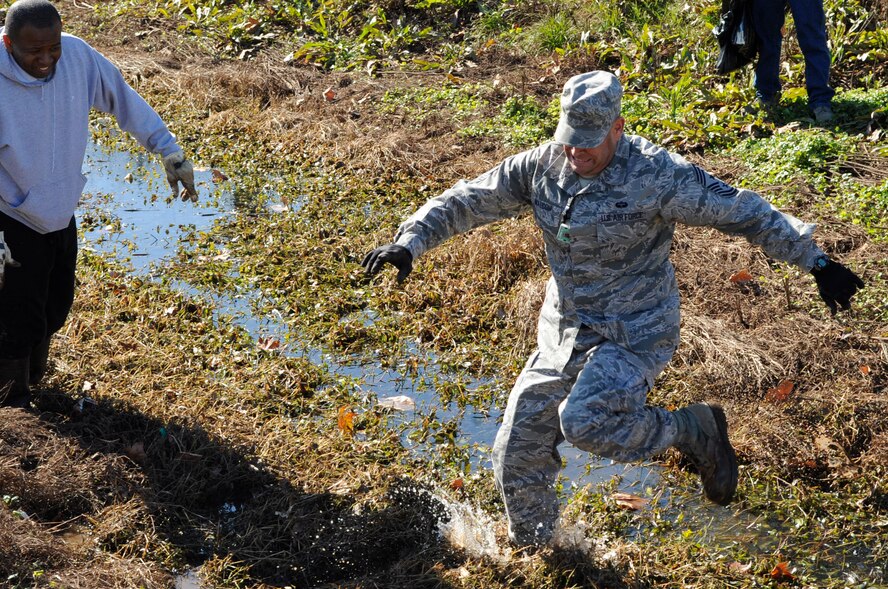 Chief Master Sgt. Larry Malcom, 2nd Bomb Wing command chief, jumps over water in a levee which runs along the north perimeter of Barksdale Air Force Base, La., Jan. 3. Malcom was one of 138 volunteers to clean up trash along the two-mile levee. Debris gets occasionally washed into the levee due to heavy rains and flooding. The levees are cleaned annually when water levels are low and the debris is visible. (U.S. Air Force photo/Airman 1st Class Andrea F. Liechti)(RELEASED)