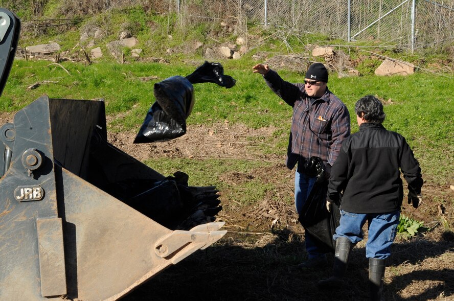 Members of Team Barksdale throw trash into a bulldozer after cleaning a levee which runs along the north perimeter of Barksdale Air Force Base, La., Jan. 3. The trash was picked up by 138 volunteers and filled the back of a dump truck. Debris gets occasionally washed into the levee due to heavy rains and flooding. The levees are cleaned annually when water levels are low and the debris is visible. (U.S. Air Force photo/Airman 1st Class Andrea F. Liechti)(RELEASED)