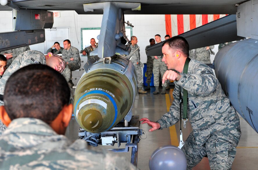 Weapons load members from the 55th Aircraft Maintenance Unit,  U.S. Air Force Staff Sgt. Christopher Goodwin(right) directs Airman 1st Class Grallian McBride(front left) to lower a joint direct attack munition while Airman 1st Class Douglas Hillman(left) observes Jan. 6, 2012, Shaw Air Force Base, S.C. The 55th, 77th and 79th Aircraft Maintenance Units weapons load crews competed against each other in a race against time. All of the load crews were tasked to load three F-16 Fighting Falcons with weapons within 35 minutes. (U.S. Air Force photo by Senior Airman Amber E. N. Jacobs/Released) 