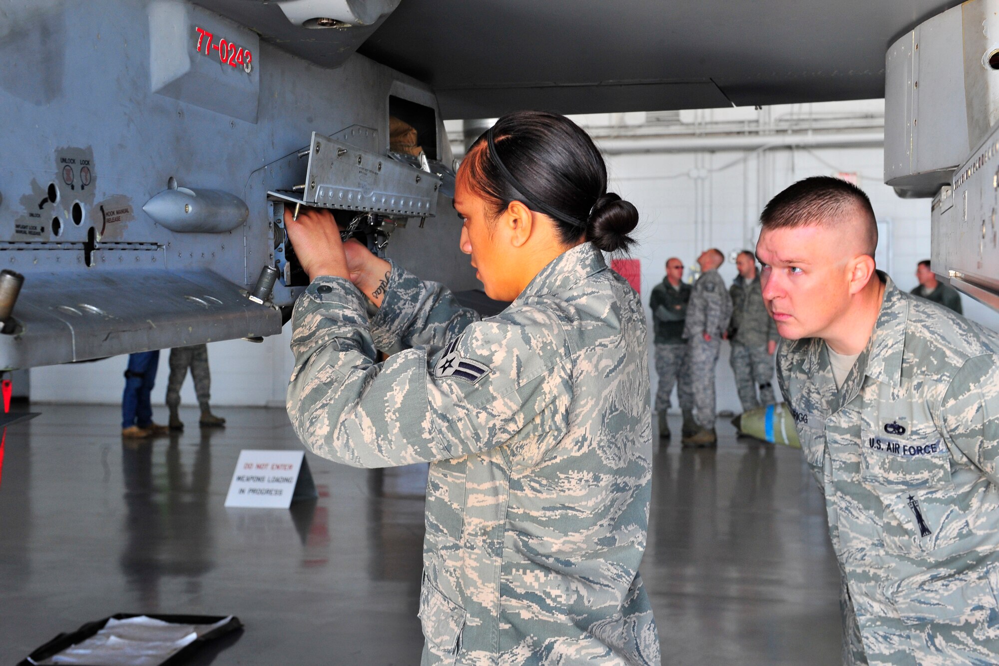 U.S. Air Force Airman 1st Class Mary Amisone, 77th Aircraft Maintenance Unit weapons load member, prepares  an F-16 Fighting Falcon to be loaded with munitions while Staff Sgt. Daniel Grigg, Weapons Standardization, judges Amisone’s progress and procedures Jan. 6, 2012, Shaw Air Force Base, S.C. The 55th, 77th and 79th Aircraft Maintenance Units weapons load crews competed against each other in a race against time. All of the load crews were tasked to load three F-16s with weapons within 35 minutes. (U.S. Air Force photo by Senior Airman Amber E. N. Jacobs/Released) 