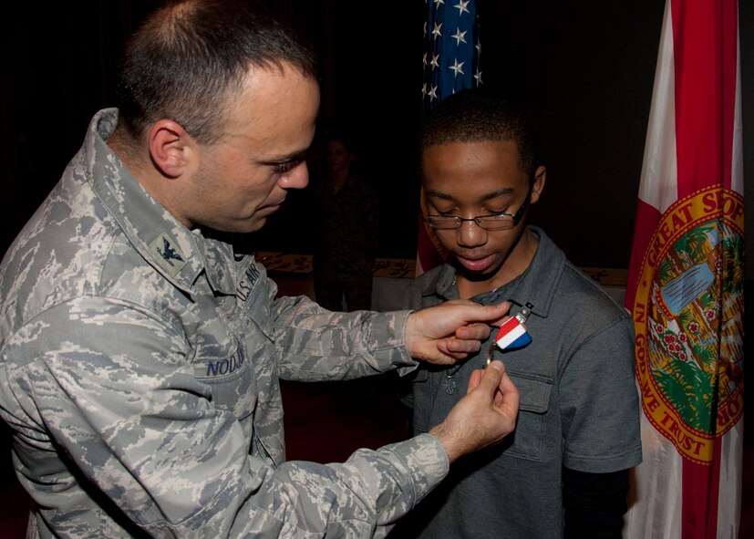 Col. Sal Nodjomian, the 96th Air Base Wing commander, pins a “Home Front Hero” blue star medal on Brayden Hall Jan. 5.  The Home Front Hero award recognizes children for their contributions to their parents’ successes in the military.  (U.S. Air Force photo/Kevin Gaddie)