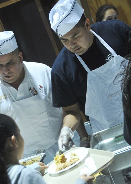 Kirtland AFB fire fighter John Toya, right, serves food Dec. 20 during “Operation Holiday Cheer.” U.S. air Force Photo by Todd Berenger