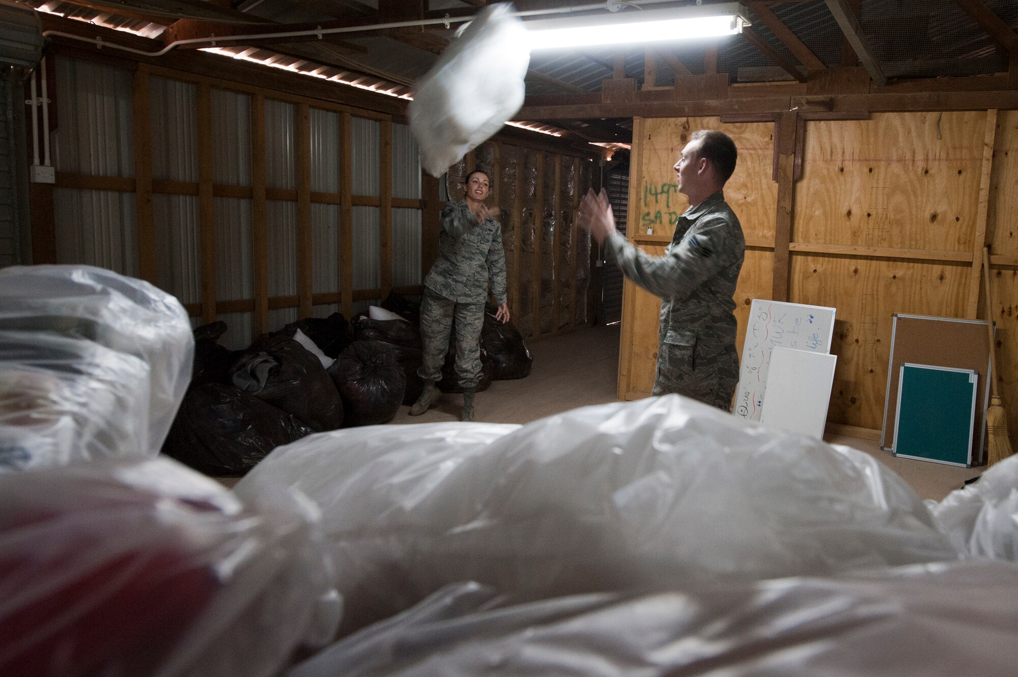 Master Sgt. Stacy Rodriguez, 332nd Expeditionary Force Support Squadron, tosses a pillow to Senior Airman Charles Sawyer, also from the 332nd EFSS, while restocking linen in the lodging warehouse on Jan. 6, 2012 at an undisclosed location in Southwest Asia. The linen was restocked after a mass cleaning due to re-deploying personnel. The warehouse is restocked weekly with clean linen to ensure the lodging flight can accommodate all personnel on base. Rodriguez is deployed from Davis-Monthan Air Force Base, Ariz., and Sawyer is deployed from Barksdale Air Force Base, La. (U.S. Air Force photo by Staff Sgt. Joshua J. Garcia/Released)
