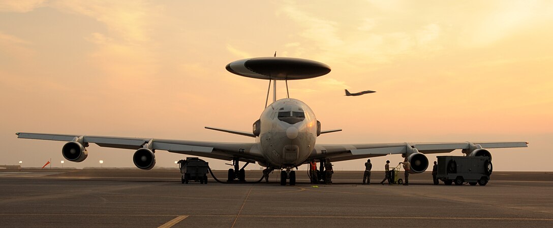 SOUTHWEST ASIA -Maintenance Airmen prepare an E-3 Sentry airborne warning and control systems aircraft for takeoff while an F-15C Eagle flies by Jan. 5, 2012. The E-3 is deployed to the 380th Air Expeditionary Wing from Tinker Air Force Base, Okla. An E-3 crew from Kadena Air Base, Japan, coordinated the rescue of a crashed AH-64 Apache helicopter crew in Afghanistan Dec. 30, 2012. (U.S. Air Force photo/Tech. Sgt. Arian Nead)

