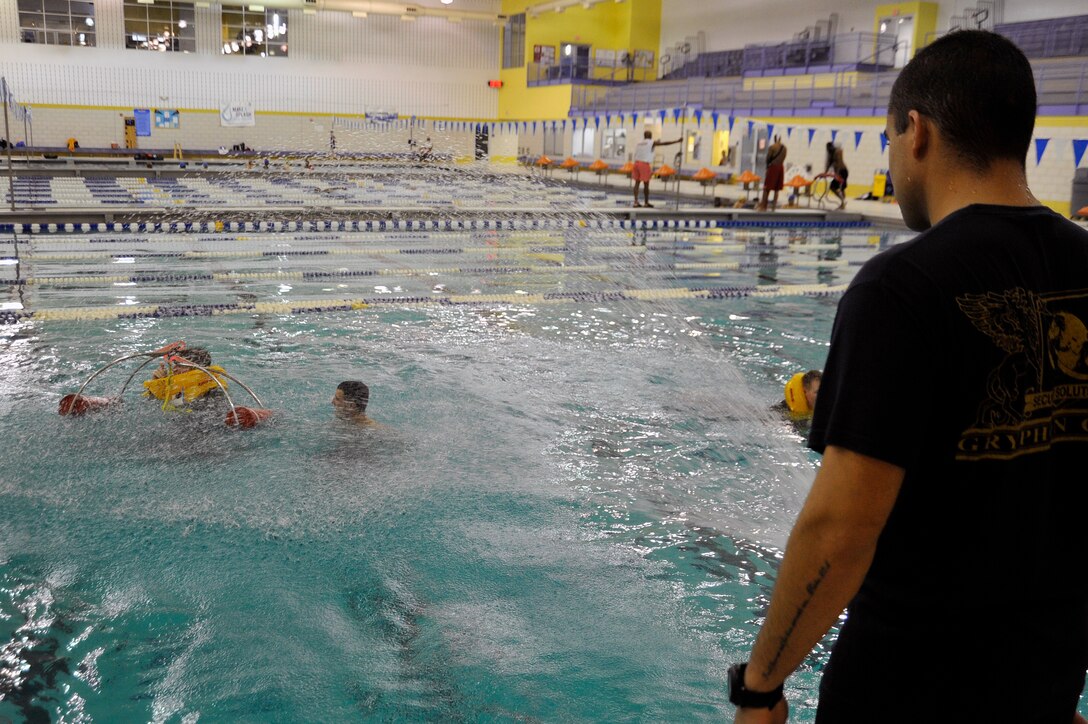 Staff Sgt. Christopher DeJesus, 89th Operations Support Squadron Survival, Evasion, Resistance, Escape specialist, sprays a hose to simulate rough water while S.E.R.E. refresher course students enter a U.S. Coast Guard rescue basket Nov. 17 at the Prince George's Sports & Learning Complex in Landover, Md. The U.S. Coast Guard rescue basket is the standard rescue basket used on all U.S. Coast Guard rescue helicopters. (U.S. Air Force Photo/Senior Airman Perry Aston)


