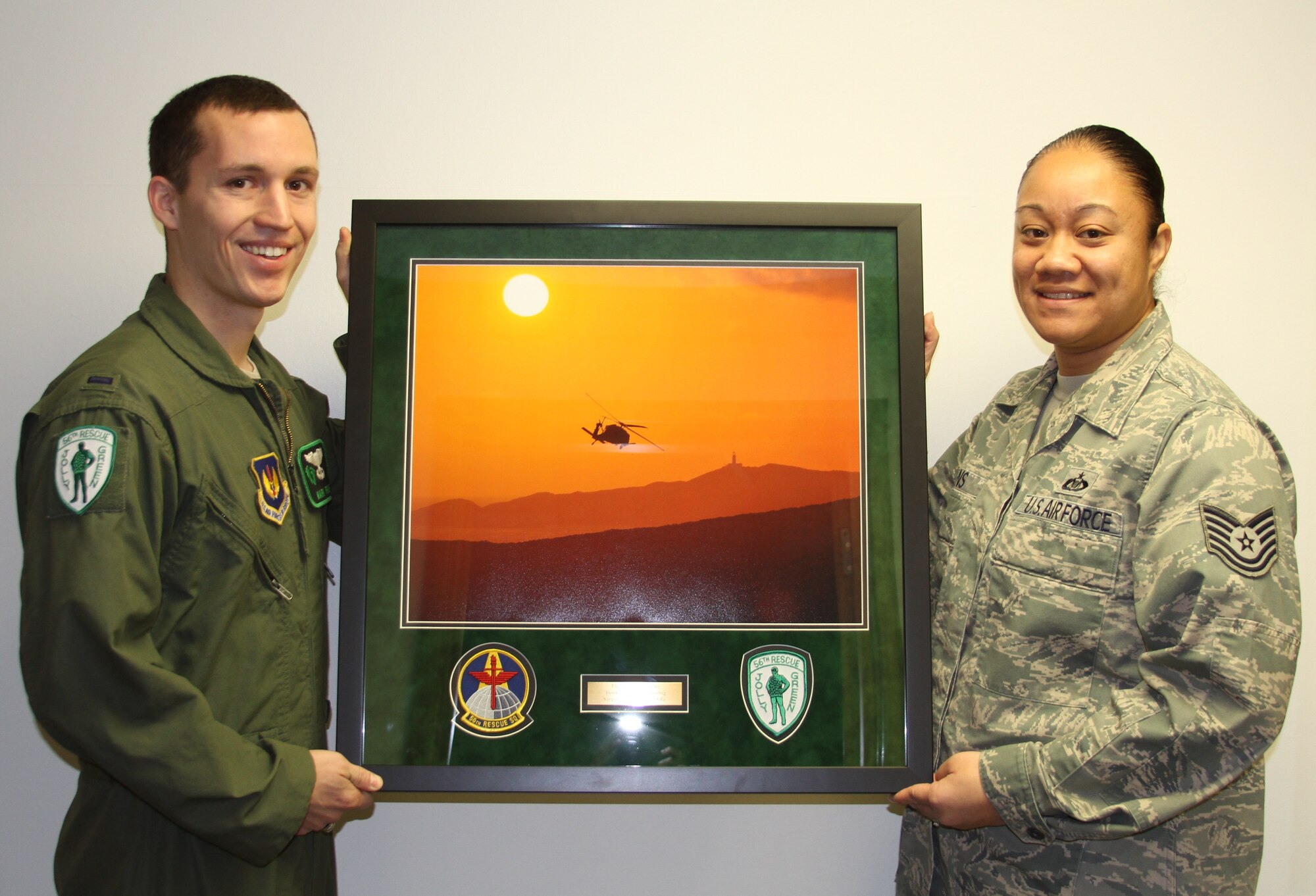 RAF MILDENHALL, England - Tech. Sgt. Jaclyn Owens (right), 352nd Special Operations Support Squadron, accepts a framed photo from 1st Lt. Mark Fraser, 56th Rescue Squadron, RAF Lakenheath, in appreciation of the crucial support she provided during Operation Odyssey Dawn. Owens speedily coordinated requests for country clearances needed in order for the 56th RQS to complete their mission in support of the operation.  (Courtesy photo)