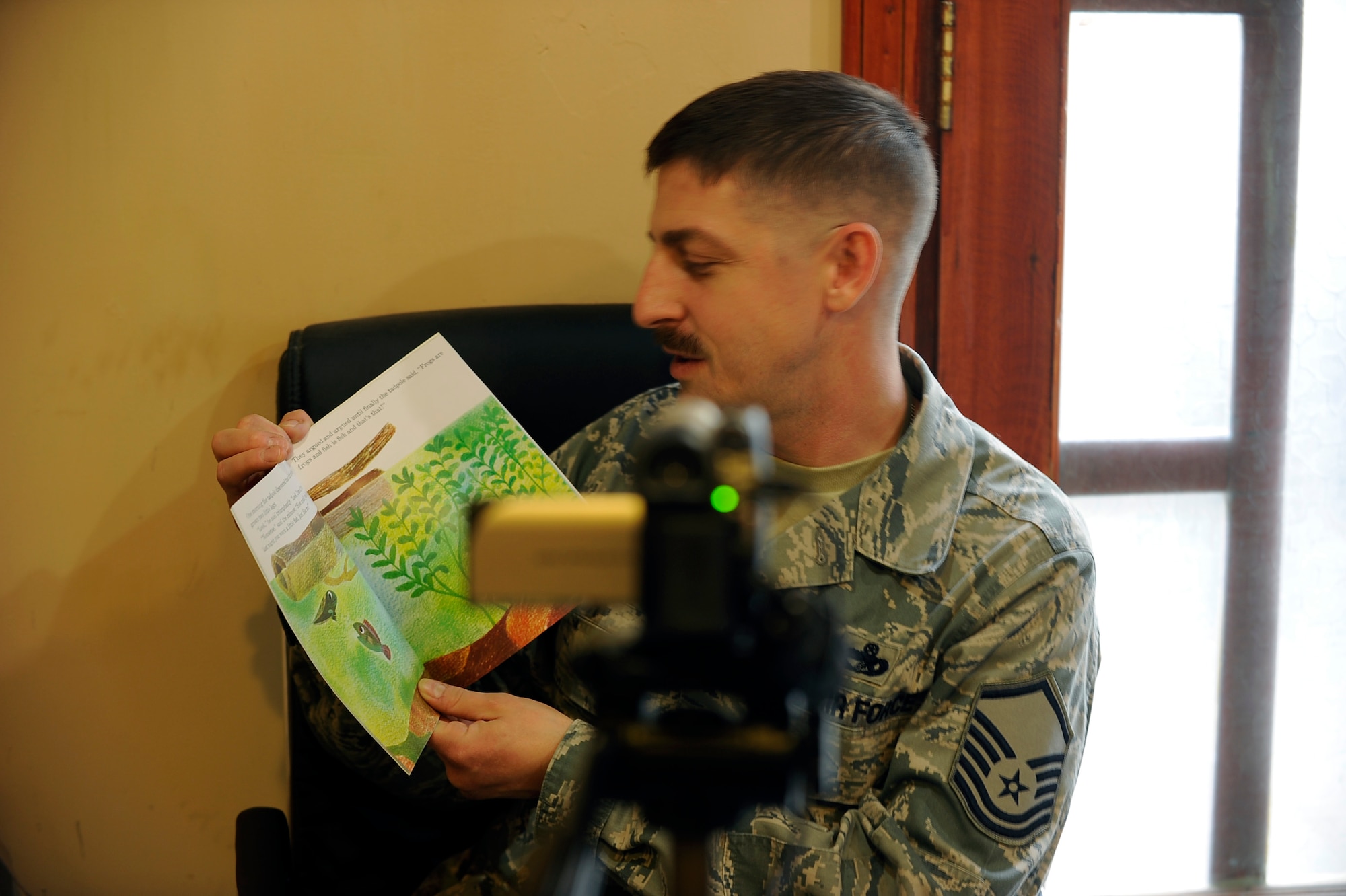 Master Sgt. Daniel Fish records a bedtime story for his daughters using the United Through Reading program at the United Services Organization at Bagram Airfield, Afghanistan, Jan. 4, 2012.  Fish is deployed from the 673rd Logistics Readiness Squadron at Joint Base Elmendorf-Richardson, Alaska.  (U.S. Air Force photo/Tech. Sgt. Vernon Cunningham)