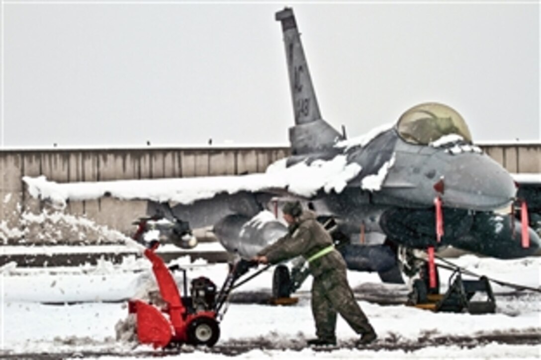 U.S. Air Force Senior Airman Joseph Rice operates a snowblower next to an F-16C Fighting Falcon on Bagram Air Field, Afghanistan, Jan. 5, 2012. Rice is a crew chief assigned to the 455th Expeditionary Aircraft Maintenance Squadron, and is deployed from the New Jersey Air National Guard's 177th Fighter Wing.