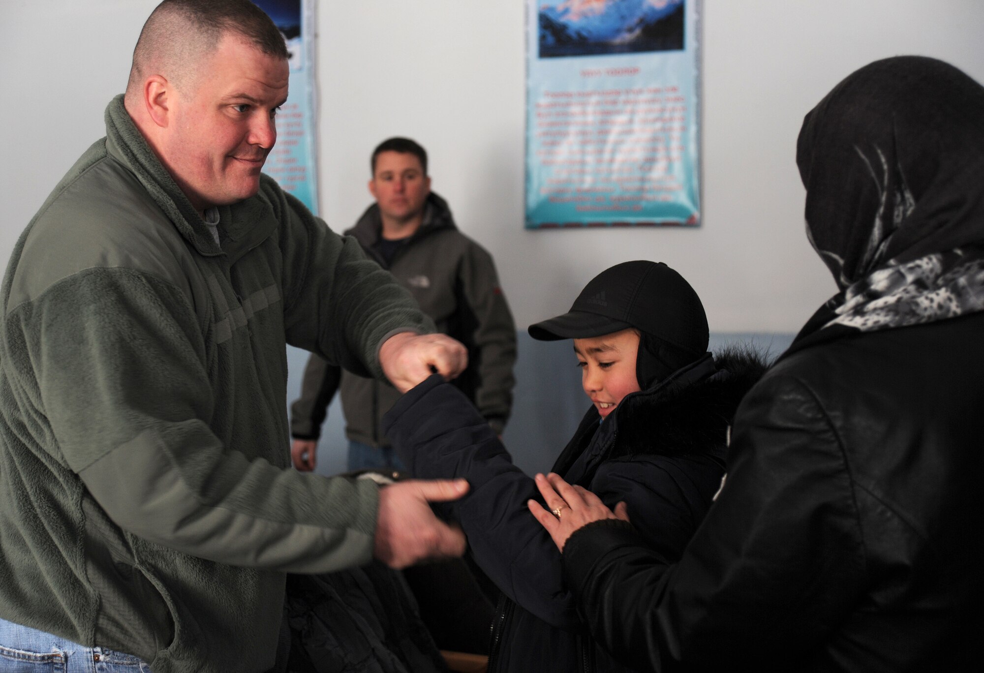While helping a 9-year-old boy named Kudred try on a new coat, Tech. Sgt. James Bunker, the executive officer for the 376th Expeditionary Operations Group at the Transit Center at Manas, looks to Kudred's mother Fatima to see if she likes how the coat fits, during an Operation Warm and Dry distribution at the Vinogradnoye Village administration building, Jan. 5, 2012, Kyrgyzstan. Bunker is deployed to the TCM from Hanscom Air Force Base, Mass., and this was his first time volunteering for a Warm and Dry event.
(U.S. Air Force photo/Master Sgt. Tracy L. DeMarco)
