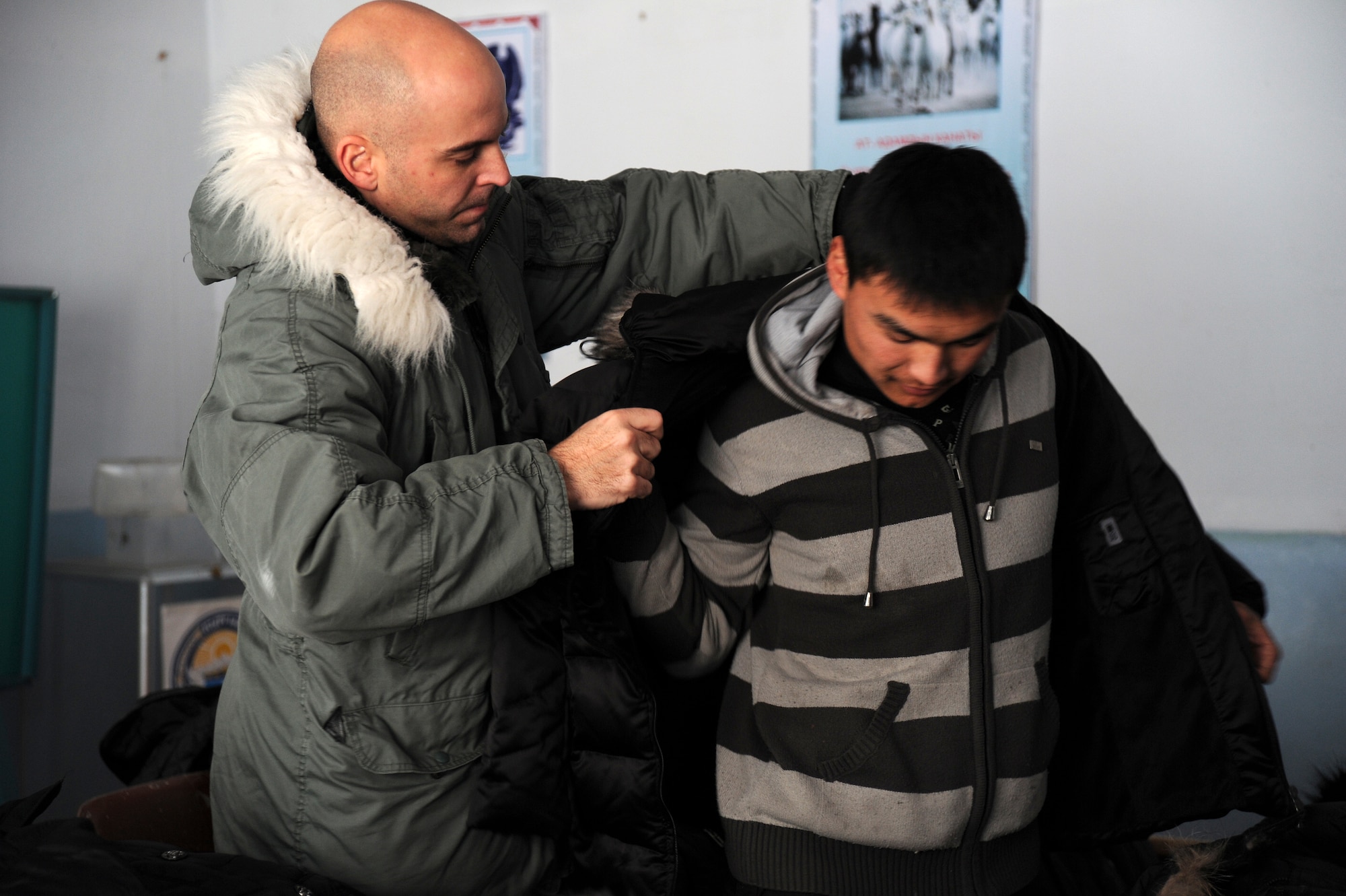 At an Operation Warm and Dry coat distribution in Vinogradnoye Village, Senior Master Sgt. James Fitch, the superintendent of the 376th Expeditionary Operations Group at the Transit Center at Manas, Kyrgyzstan, helps Esen try on a new coat, Jan. 5, 2012. More than 50 coats were given away by Fitch and seven additional volunteers from the Transit Center at Manas. "This can be a very eye-opening experience for our young Airmen who've never interacted with people from a third world country," Fitch said. Fitch is deployed here from Fairchild Air Force Base, Wash. In its third year of execution, Operation Warm and Dry is a humanitarian assistance program ran by the Theater Security Cooperation division at the TCM in partnership with the U.S. Embassy in Kyrgyzstan and the Kyrgyz Republic.
(U.S. Air Force photo/Master Sgt. Tracy L. DeMarco)
