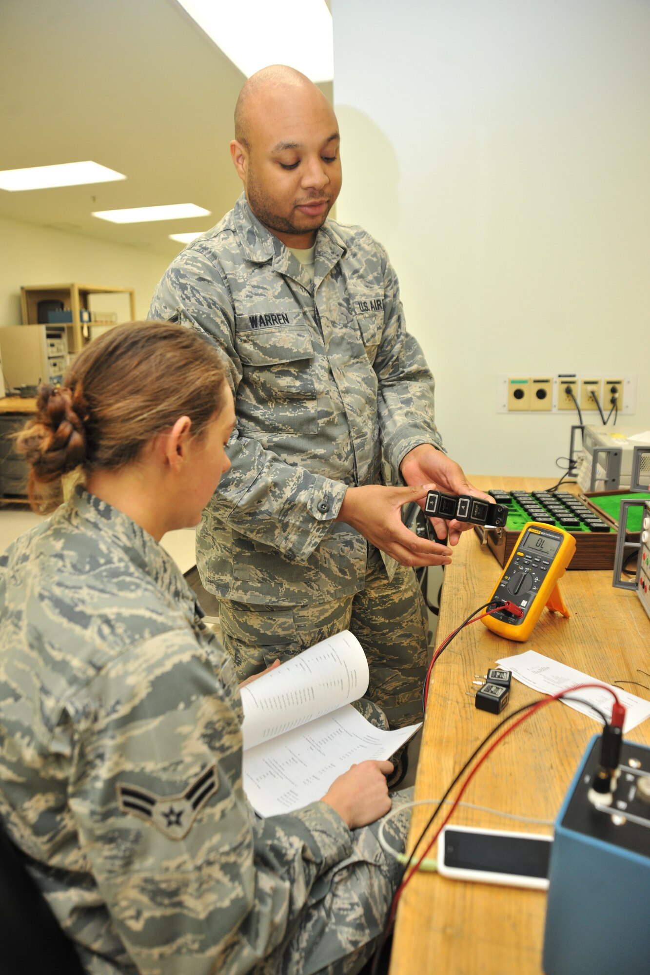 Senior Airman Kenny Warren, 8th Maintenance Squadron precision and measurement equipment laboratory journeyman, shows Airman 1st Class Kayleigh McGill, 8th MXS PMEL apprentice, the proper way to use a piece of equipment during her upgrade training at Kunsan Air Base, Republic of Korea, Jan. 5, 2012. Precision and measurement equipment laboratory specialists are responsible for calibrating equipment used in virtually every phase of maintenance for nearly every piece of equipment the Air Force operates. (U.S. Air Force photo by Senior Airman Brittany Y. Auld/Released)