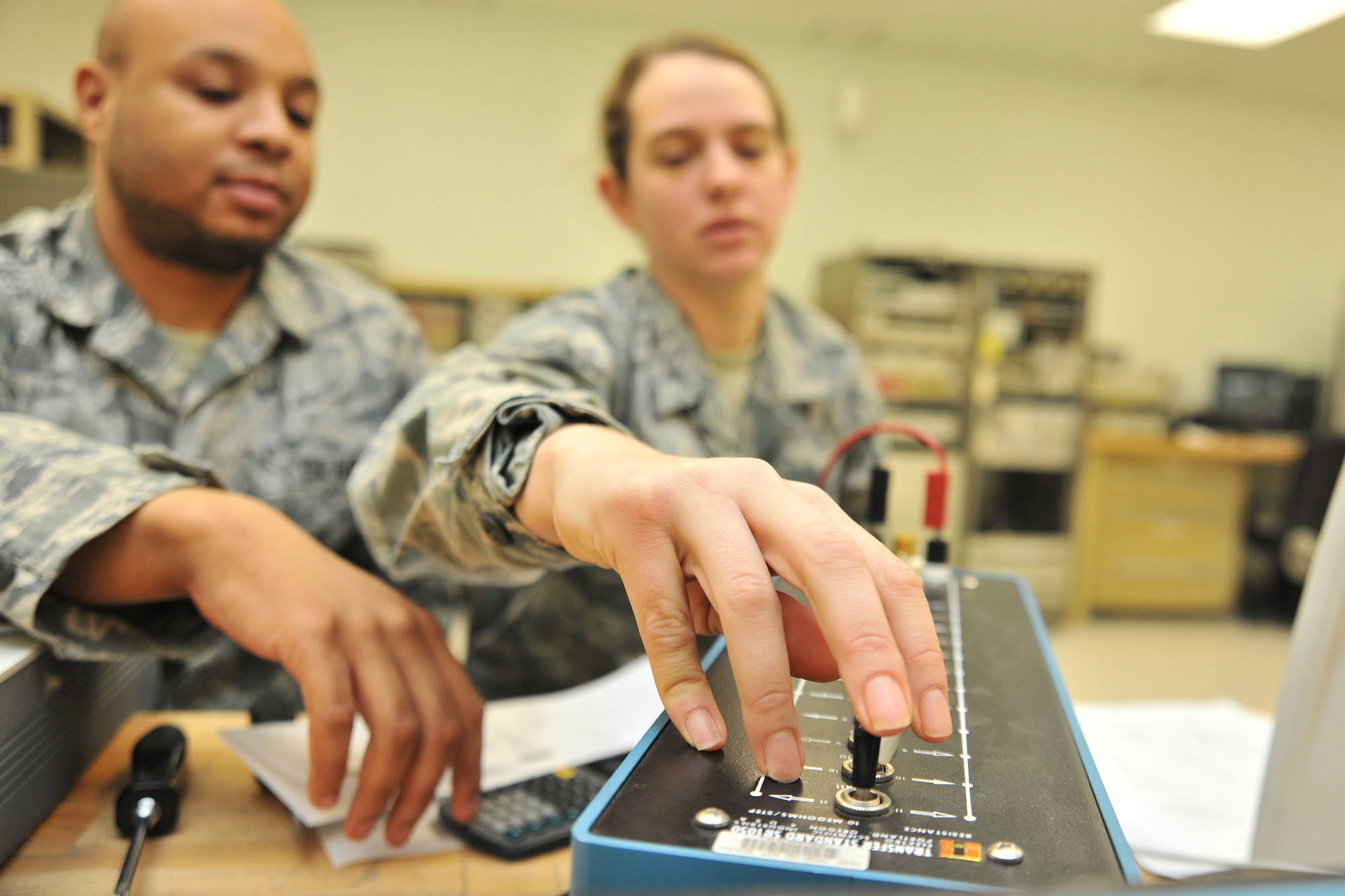 Airman 1st Class Kayleigh McGill, 8th Maintenance Squadron precision and measurement equipment laboratory apprentice, receives hands-on training with a resistance standard from Senior Airman Kenny Warren, 8th MXS PMEL journeyman, during her upgrade training at Kunsan Air Base, Republic of Korea, Jan. 5, 2012. Precision and measurement equipment laboratory specialists are responsible for calibrating equipment used in virtually every phase of maintenance for nearly every piece of equipment the Air Force operates. (U.S. Air Force photo by Senior Airman Brittany Y. Auld/Released)