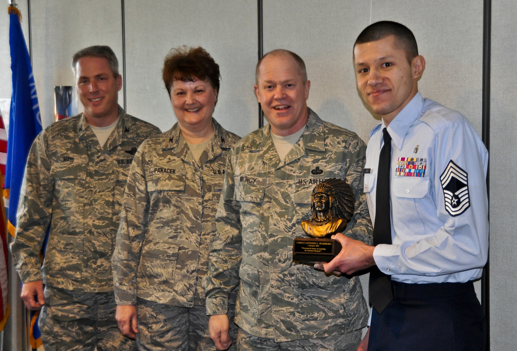 Command Chief Master Sgt. Christopher E. Muncy, command chief of the Air National Guard, presents recently promoted Chief Master Sergeant Antonio Marrero of the 128th Air Refueling Wing's medical group with a chief's bust in Milwaukee on January 08, 2012. 128 ARW Vice Commander Colonel Michael Mayo and Medical Group Commander Colonel Eileen Panacek provided a precursor history of the award and a list of accolades for CMSgt Marrero. Muncy was at the 128 ARW in part of tour of all the Air National Guard bases located in Wisconsin. USAF Photograph by Staff Sgt. Jeremy Wilson