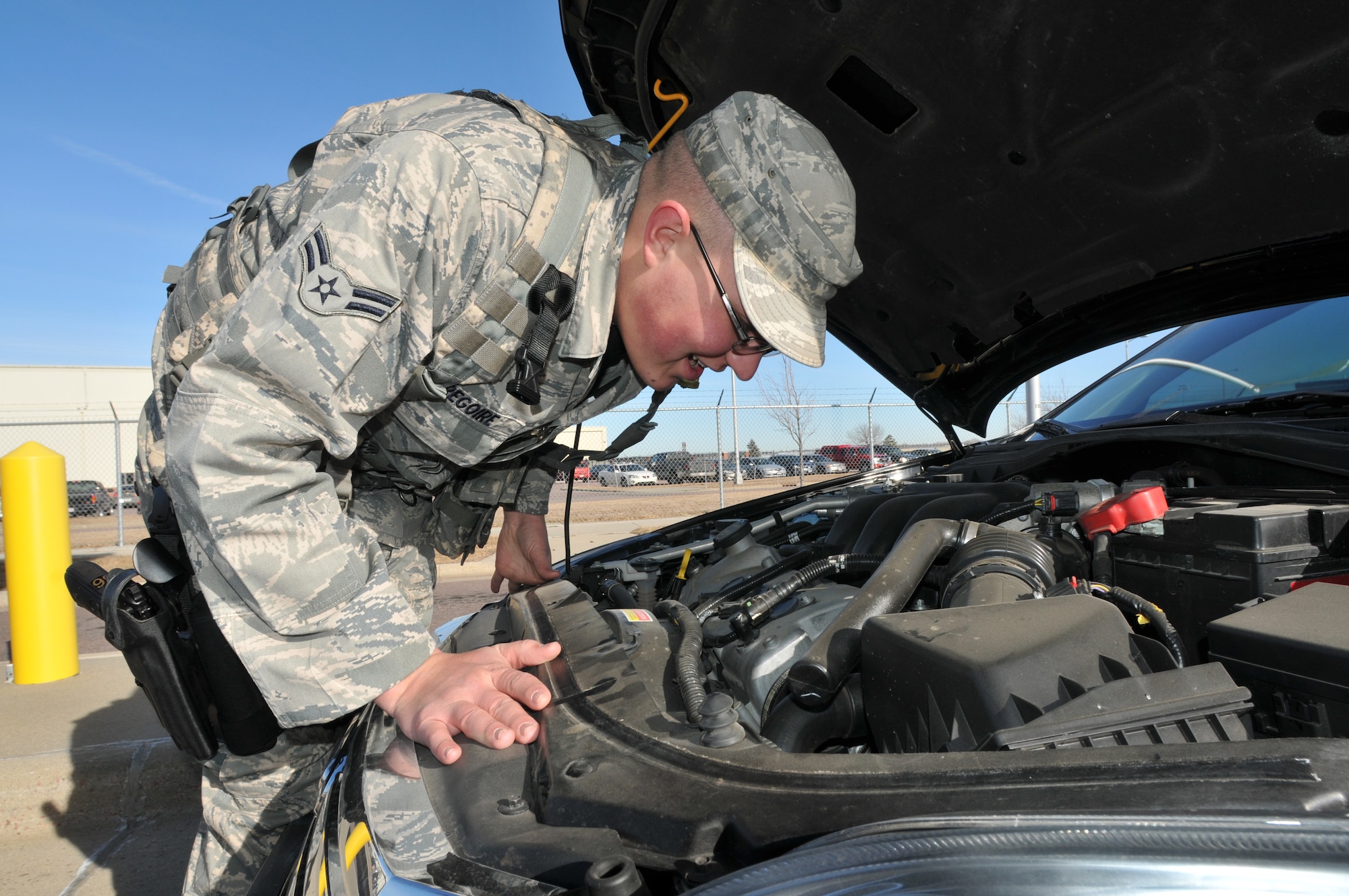 Sioux Falls, S.D. –Airman 1st Class Tyson Gregoire, 114th Security Forces Squadron, searches the engine compartment of a car while conducting a random vehicle search at the main gate at Joe Foss Field, Jan. 7.  Security personnel have been enjoying the unseasonable warm weather in South Dakota this winter. (National Guard photo by Tech. Sgt. Quinton Young)(Released)