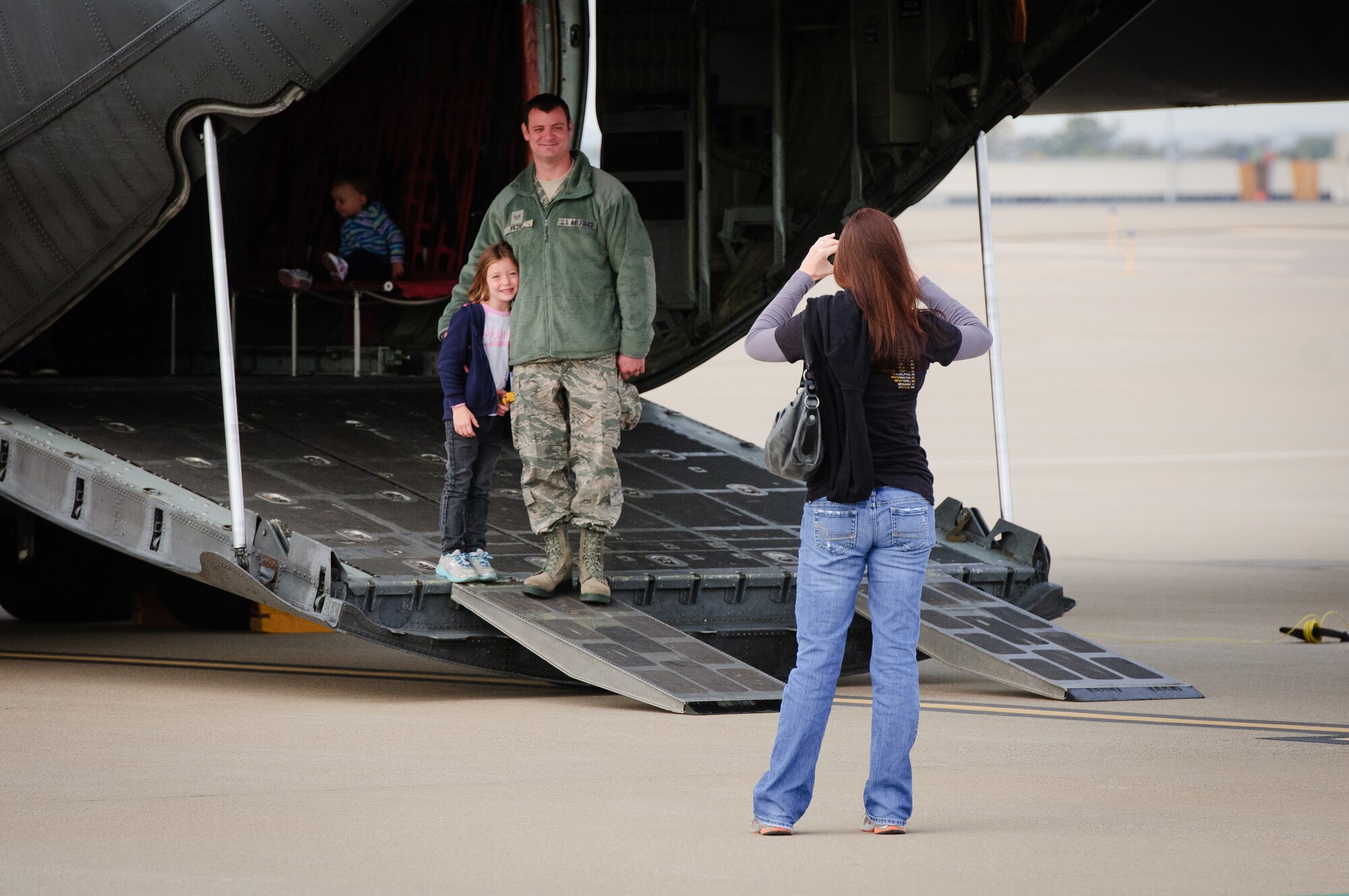 Amanda Fazio takes a photo of her daughter, Ava, and husband, Staff Sgt. Chad Fazio, an electrician with the Kentucky Air Guard's 123rd Civil Engineer Squadron, as they tour a C-130 aircraft on the flight line of the Air Guard Base in Louisville, Ky., on Oct. 23, 2011. The display was part of Family Day activities that drew more than 1,000 to the 123rd Airlift Wing. (U.S. Air Force photo by Senior Airman Maxwell Rechel)