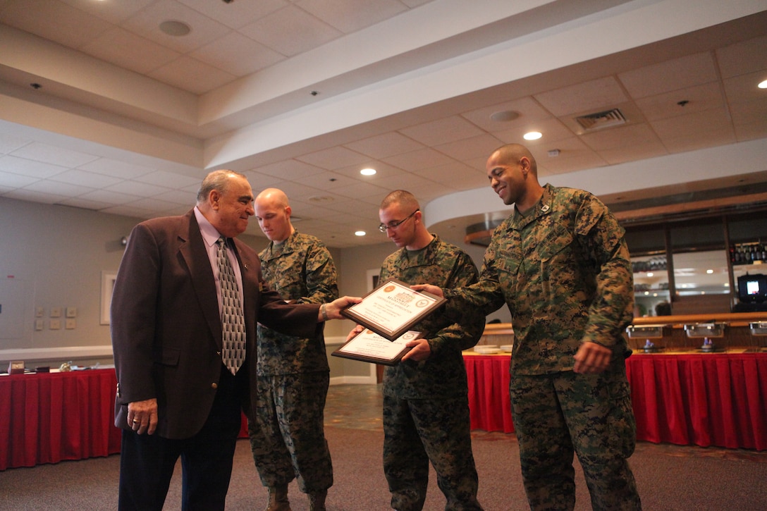 John Reed, executive director with Mainstreet hands plaques to Sgt. Robert F. Lark, an expeditionary airfields systems technician with Marine Wing Support Squadron 273, Marine Wing Support Group 27, 2nd Marine Aircraft Wing, Marine Corps Air Station Beaufort, Cpl. Matthew S. Hamel, a distribution management specialist with Company A, Headquarters and Headquarters Squadron, Marine Corps Air Station Beaufort and Petty Officer 2nd Class Francisco Aquedamartinez, a corpsman with Deployment Processing Command-East, MCB Camp Lejeune during the 6th annual Marine Corps Installations East breakfast hosted by Mainstreet at the Ball Center aboard Marine Corps Base Camp Lejeune, Jan. 9. The recognized Marines also received the Navy Marine Corps Achievement medal.