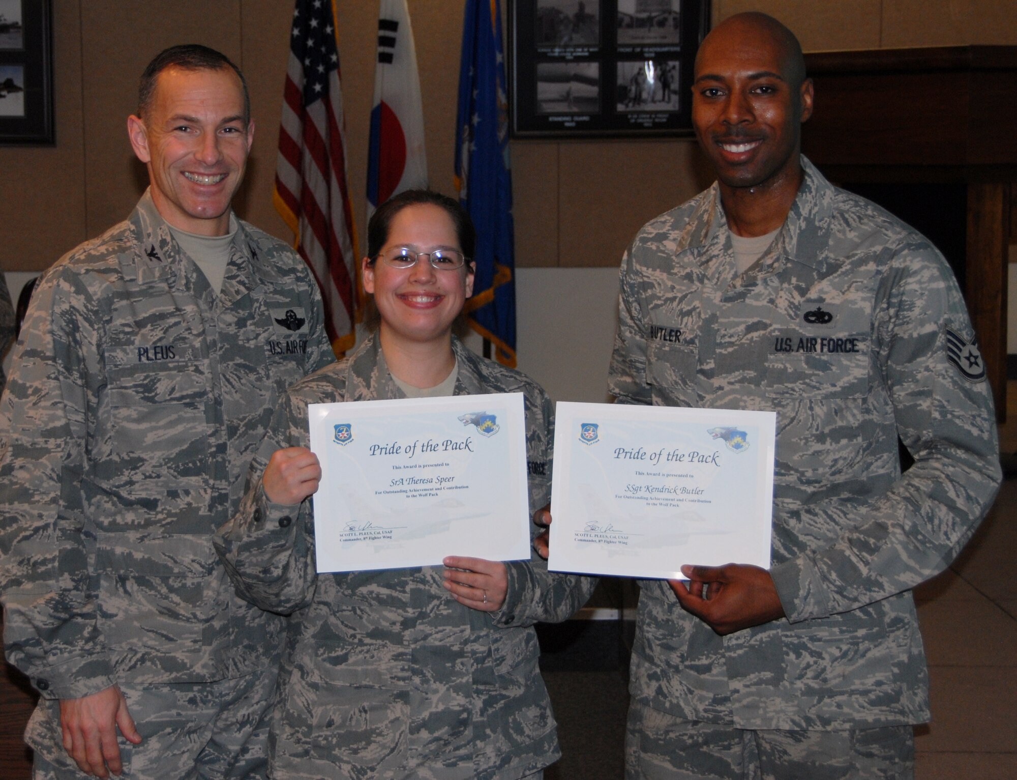 Col.  Scott L. Pleus, 8th Fighter Wing commander, presents Senior Airman Theresa Speer, 8th MXS avionics intermediate technician, and Staff Sgt. Kendrick Butler, 8th Aircraft Maintenance Squadron metals technology shift supervisor, with Kunsan’s Pride of the Pack.  Pride of the Pack recognizes the outstand work Airmen do every day. (U.S. Air Force photo by Capt. Omar Villarreal/ Released)