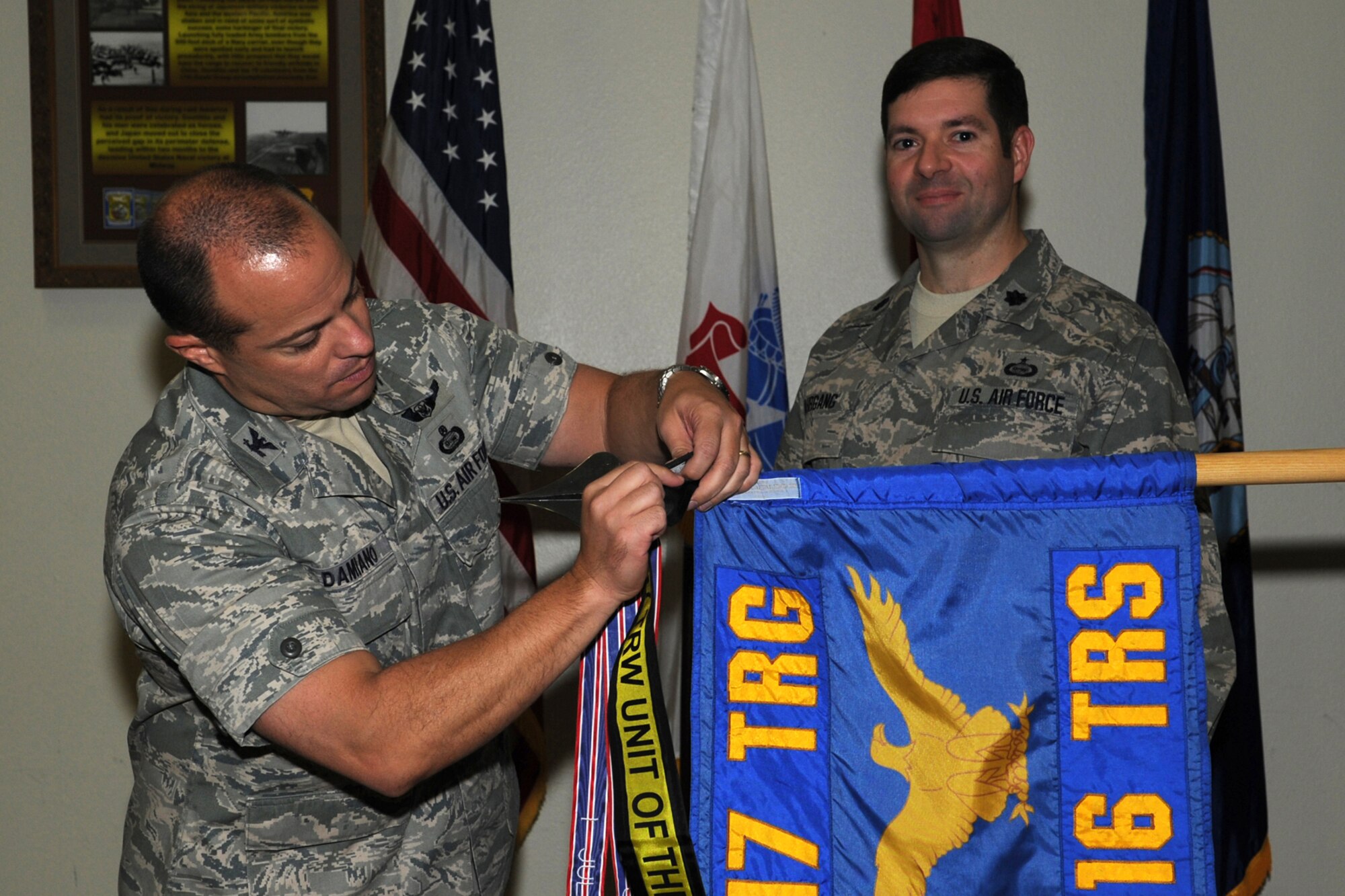 GOODFELLOW AIR FORCE BASE, Texas -- Col. Mark Damiano, 17th Training Wing Commander, places the 17th Training Wing Unit of the Quarter streamer on the 316th Training Squadron guidon as Lt. Col. Scott Nahrgang, 316th TRS Commander, stands back during the wing quarterly awards ceremony Jan. 5. (U.S. Air Force photo/Staff Sgt. Laura R. McFarlane)