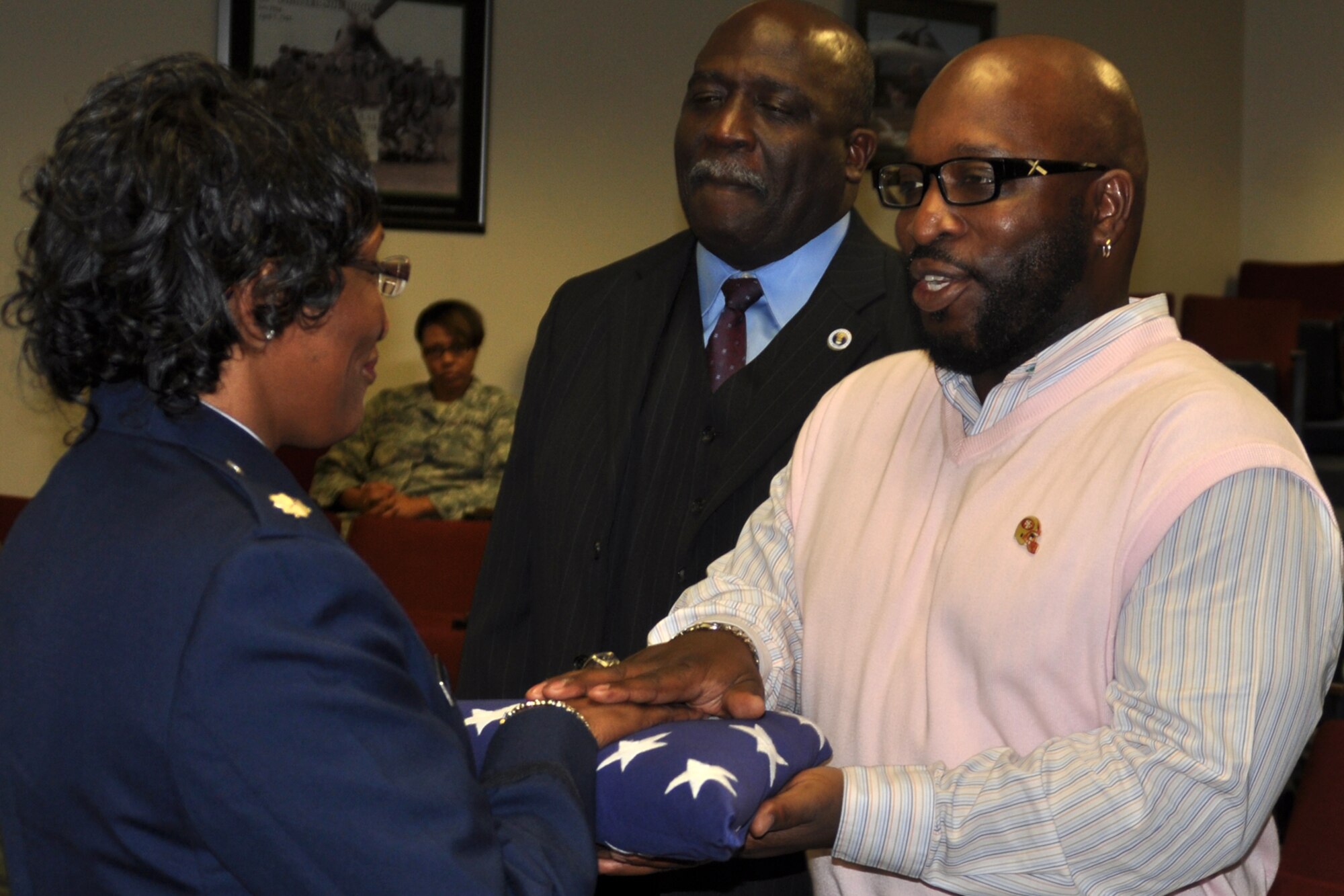 Retired Lt. Col. Corine Barral-Sutton symbolically presents an America Flag to her son James, during her retirement ceremonies at Barksdale Air Force Base, La., Jan. 7, 2012. Barral-Sutton, who was assigned to the 307th Medical Squadron, retired after 23 years of service. (U.S. Air Force photo by Master Sgt. Jeff Walston/Released)      