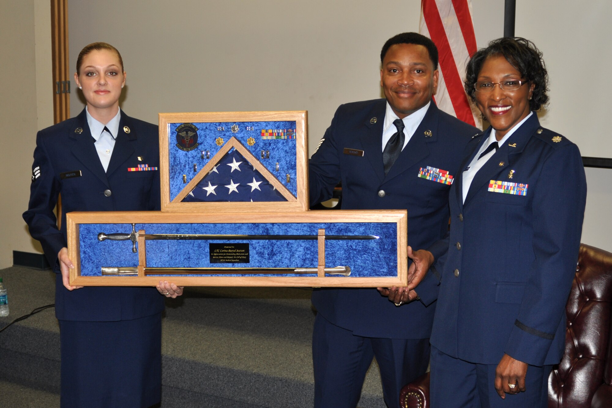 Senior Airman Jennifer Neuyen, a medical service journeyman, and Tech. Sgt. David Walker, a pharmacy technician, present a shadow box to retired Lt. Col. Corine Barral-Sutton during retirement ceremonies at Barksdale Air Force Base, La., Jan. 7, 2012. Barral-Sutton, who was assigned to the 307th Medical Squadron retired after 23 years of service. Neuyen and Walker are also assigned to the 307th Medical Squadron at Barksdale AFB. (U.S. Air Force photo by Master Sgt. Jeff Walston/Released)      