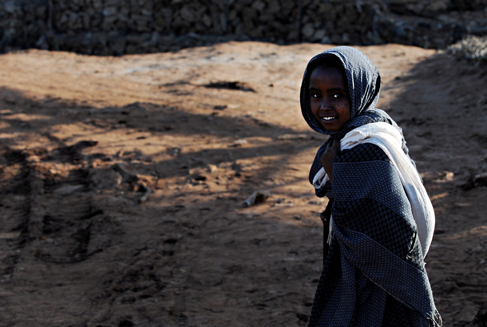 A young girl pauses and smiles as she walks toward the original river crossing in Negele Borena, Ethiopia, Dec. 5, 2011. U.S. Navy sailors from Naval Mobile Construction Battalion 5 recently completed a bridge for pedestrians and livestock, which will prevent people from fording through the river to cross it. (U.S. Air Force photo/Senior Airman Jarad Denton)