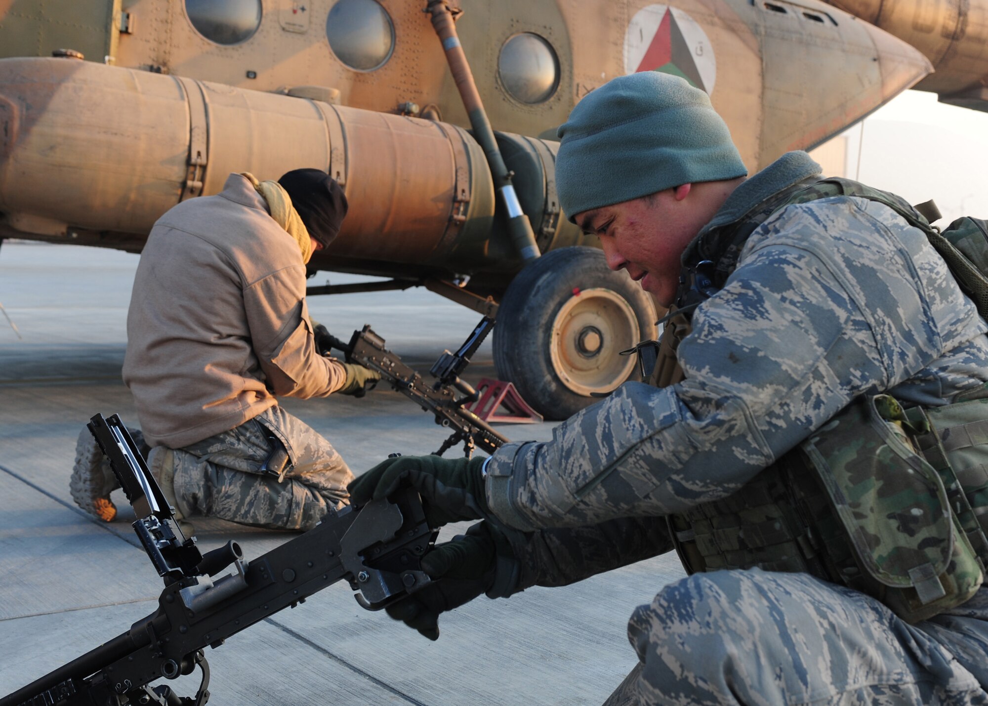 Tech. Sgt. Jerry Sayasene and Tech. Sgt. Matthew Chambers, flight engineers with the 438th Air Expeditionary Advisory Squadron, perform operations checks on M240 machine guns prior to a supply flight over northern Afghanistan, Dec. 21, 2011, at Kabul International Airport. Both Sayasene and Chambers are currently deployed to provide advisory training for Afghan air force flight engineers. (U.S. Air Force photo by Staff Sgt. Nadine Y. Barclay)