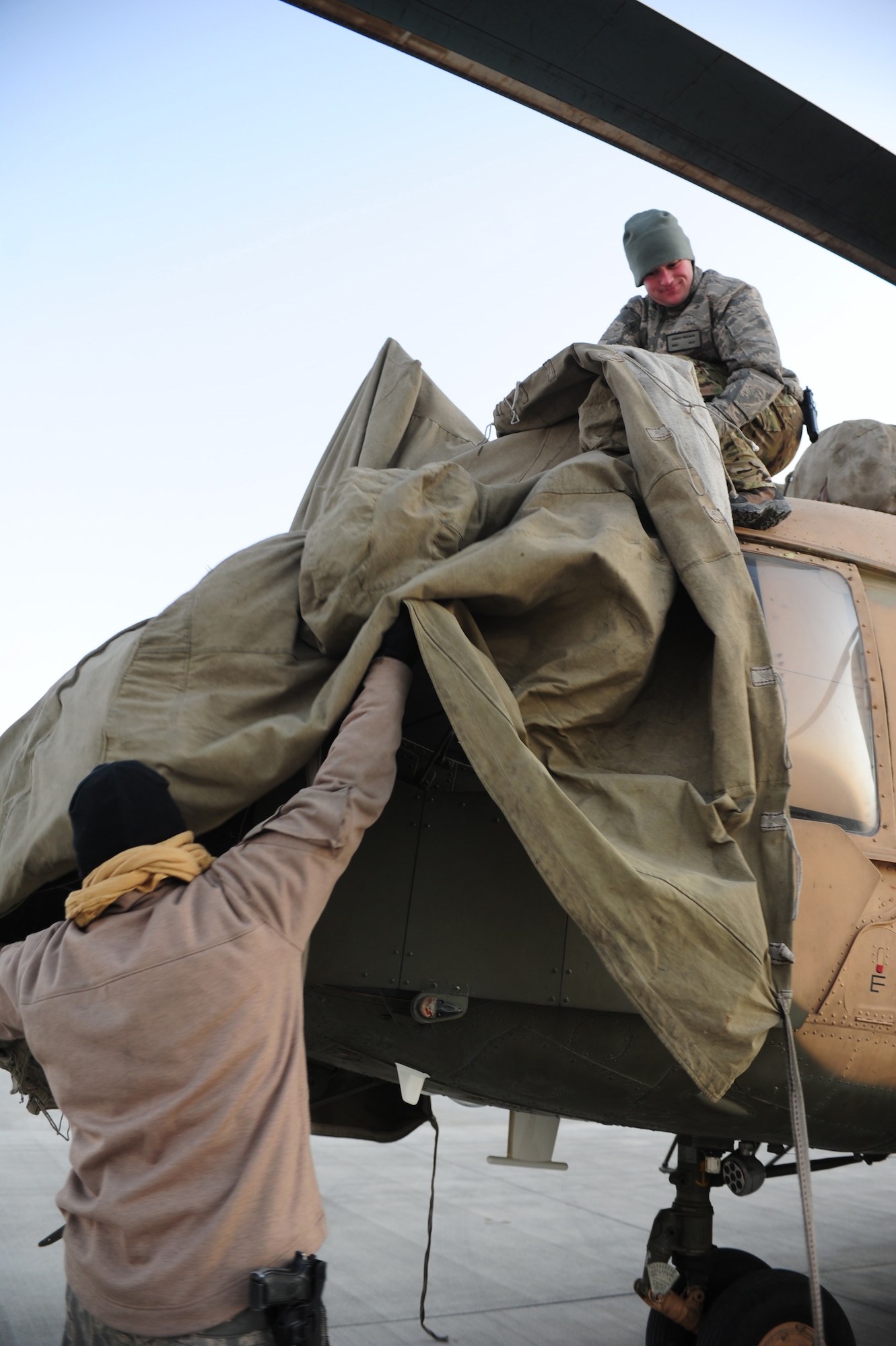 U.S. Air Force flight crew personnel remove airframe covers from an Afghan air force MI-17 helicopter in preparation for a supply mission over northern Afghanistan, Kabul International Airport, Dec. 21, 2011.  (U.S. Air Force photo by Staff Sgt. Nadine Y. Barclay)