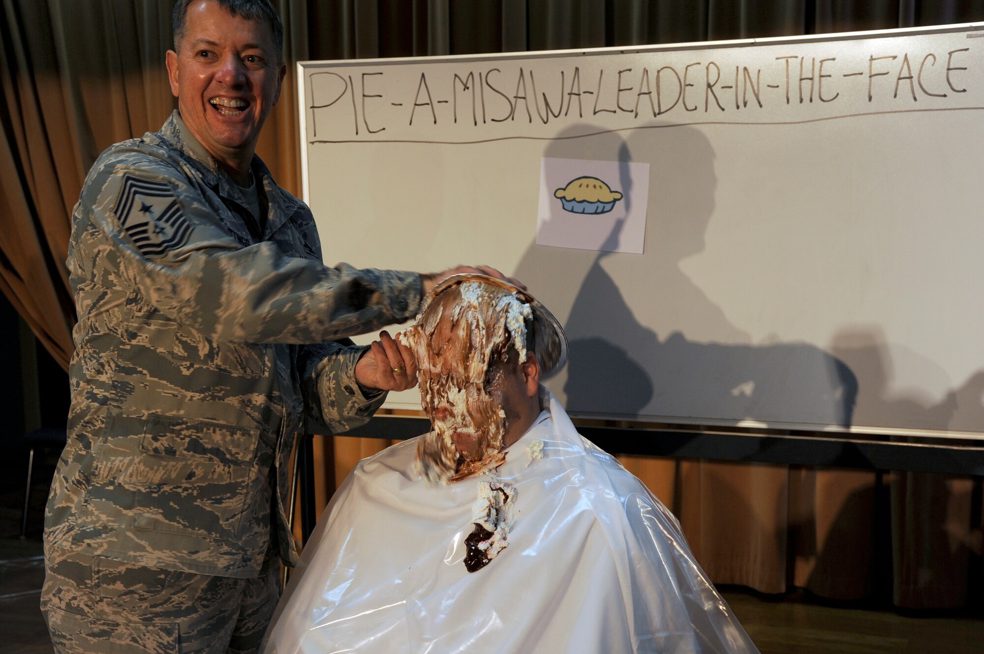 MISAWA AIR BASE, Japan - Chief Master Sgt. Russell Hastings, 35th Fighter Wing command chief, rubs a whipped-cream pie in the face of Maj. Corey Gibbs, 35th Comptroller Squadron commander, during the annual awards banquet "pie-in-the-face" fundraiser event here, Jan. 10. The awards banquet committee held the fundraiser with proceeds used toward awards, prizes, complimentary gifts and ticket price reduction. (U.S. Air Force photo/Tech. Sgt. Marie Brown)