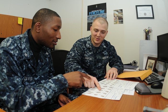 Petty Officer 3rd Class Ryan Davis (left) and Petty Officer 2nd Class Eric Martin review the Standard Form 87 fingerprint card and other important paperwork to ensure their accuracy prior to the forms being mailed to the Electronic Questionnaire for Investigation Processing department at  the Office of Personnel Management in Boyers, Pa. Martin is a Machinist’s Mate assigned to the 628th Security Forces Squadron Information Protection office at Joint Base Charleston – Weapons Station and Davis is a Ship’s Serviceman assigned to Naval Support Activity’s Unaccompanied Personnel Housing office at JB Charleston-Weapons Station. (U.S. Navy photo/Petty Officer 1st Class Jennifer Hudson)