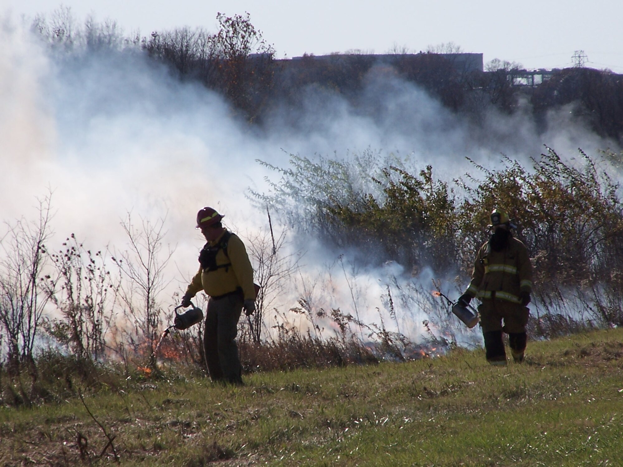Fire fighters from Wright-Patterson Air Force Base and neighboring Bath Township work with Ohio Department of Natural Resources wildlife officials to light part of Huffman Prairie in 2009.  Base officials are planning another controlled burn sometime this month to help maintain and expand prairie vegetation and prevent the spread of invasive woody species. (U.S. Air Force Photo by Ted Theopolos)