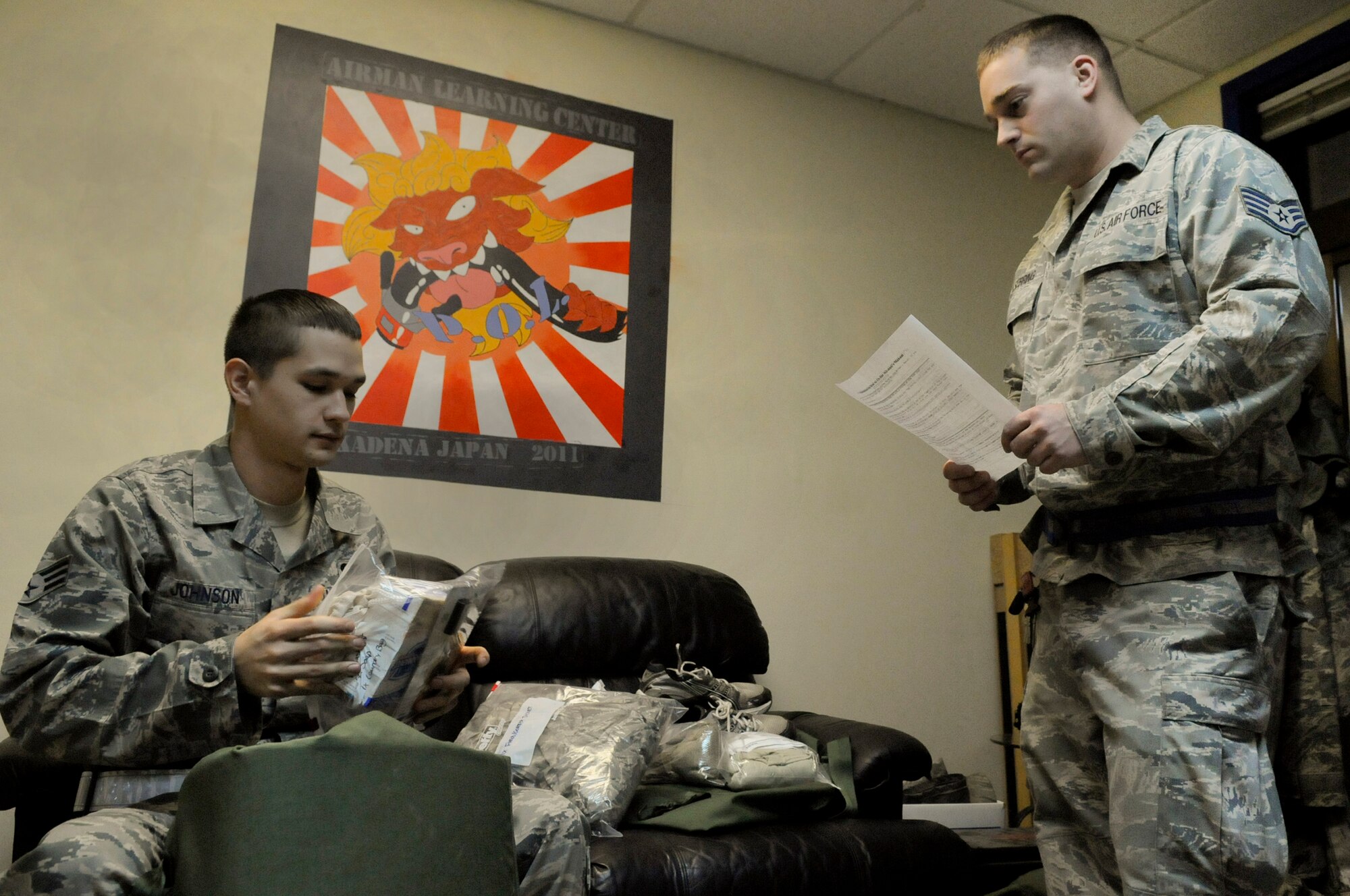 U.S. Air Force Staff Sgt. Robert Sebring, 18th Logistics Readiness Squadron fuels distribution supervisor, reviews mobility bag requirements with Senior Airman Ben Johnson, 18th LRS refueling unit operator, during local operational readiness exercise Beverly High 12-2, on Kadena Air Base, Japan, Jan. 10, 2012. Airmen are required to maintain a mobility bag with required items in case they are called for a real-world deployment. (U.S. Air Force photo by Airman 1st Class Tara A. Williamson/Released)