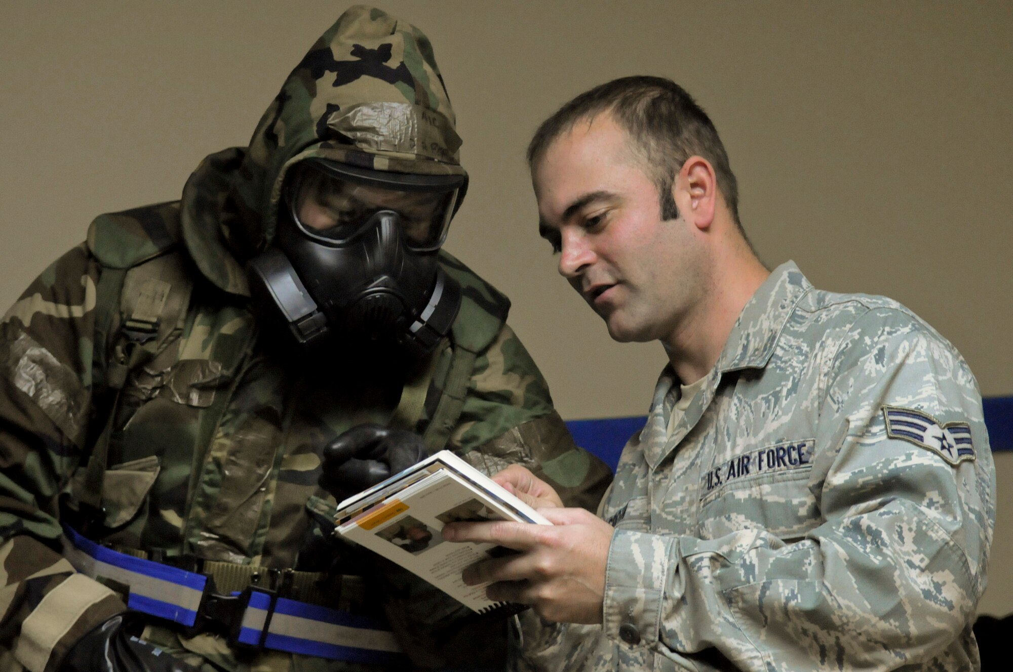 U.S. Air Force Senior Airman Christian Groth, 18th Logistics Readiness Squadron refueling unit operator, advises U.S. Air Force Airman 1st Class Raymond Borja, 18th LRS refueling unit operator, of proper procedures while donning mission-oriented protective posture gear during local operational readiness exercise Beverly High 12-2, on Kadena Air Base, Japan, Jan. 10, 2012. Kadena performs LOREs on a regular basis to keep Airmen proficient on mobility, deployment, reception, bedding down of forces, employment and self-aid and buddy care, for possible real-world contingencies. (U.S. Air Force photo by Airman 1st Class Tara A. Williamson/Released)
