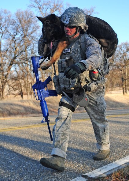 Staff Sgt. Bryan Bowermaster, 9th Security Forces Squadron military working dog handler, carries his dog Edy during a ruck march Jan. 9, 2012 behind the Beale AFB clinic. In the event of a stream crossing or an injury the dogs have to be used to this treatment and the Airman have to be able to perform the task comfortably. (U.S Air Force photo by Senior Airman Shawn Nickel/Released)