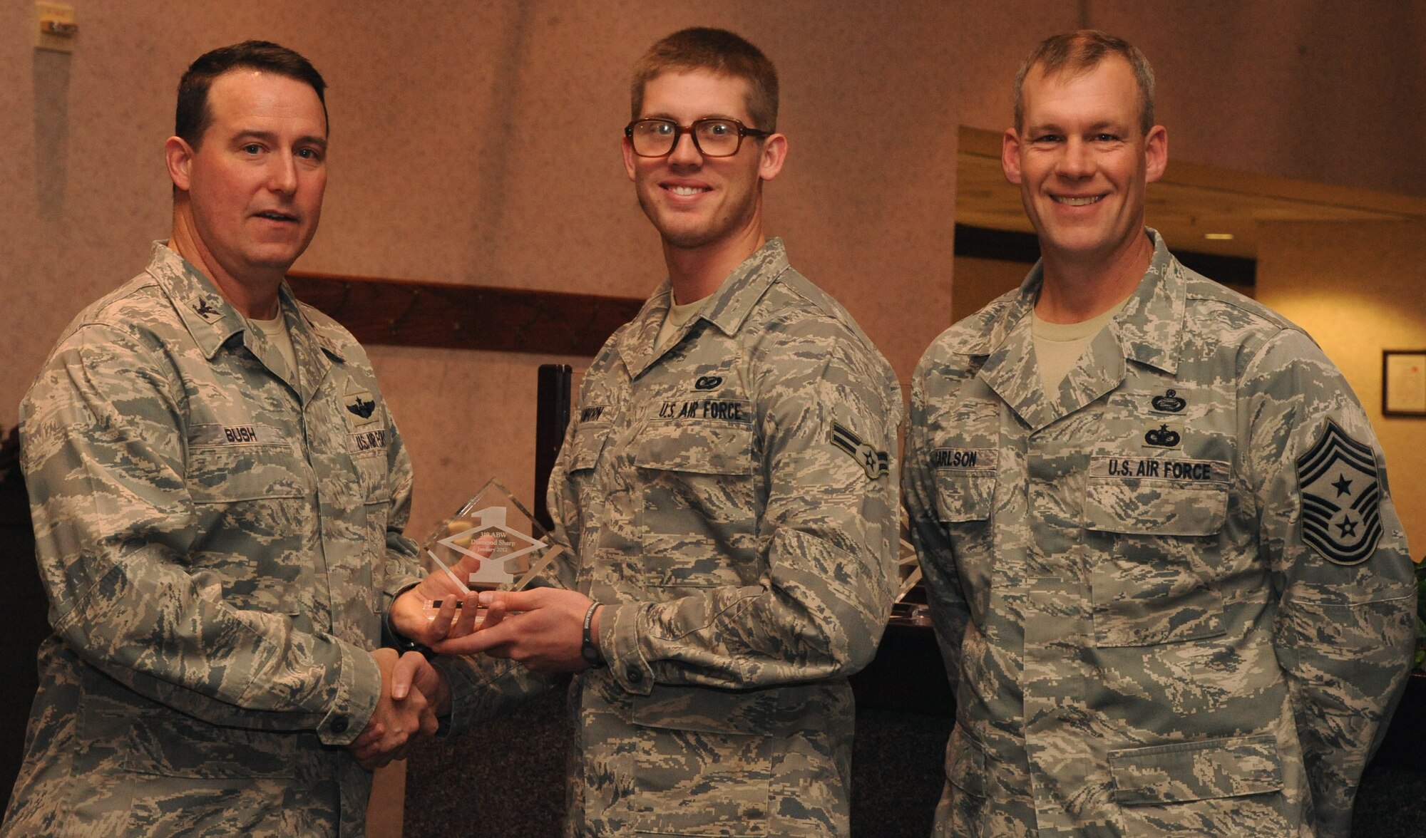 Col. Timothy Bush, 319th Air Base Wing commander, presents Airman 1st Class Derek Vanhorn, 319th Public Affairs, with a Diamond Sharp Award Jan. 10 on Grand Forks Air Force Base, N.D., accompanied by 319th ABW Command Chief Master Sgt. David Carlson. The Diamond Sharp Award is given to Airmen who epitomize service before self and strive for excellence at work and off duty. (U.S. Air Force photo by Airman 1st Class Xavier Navarro)