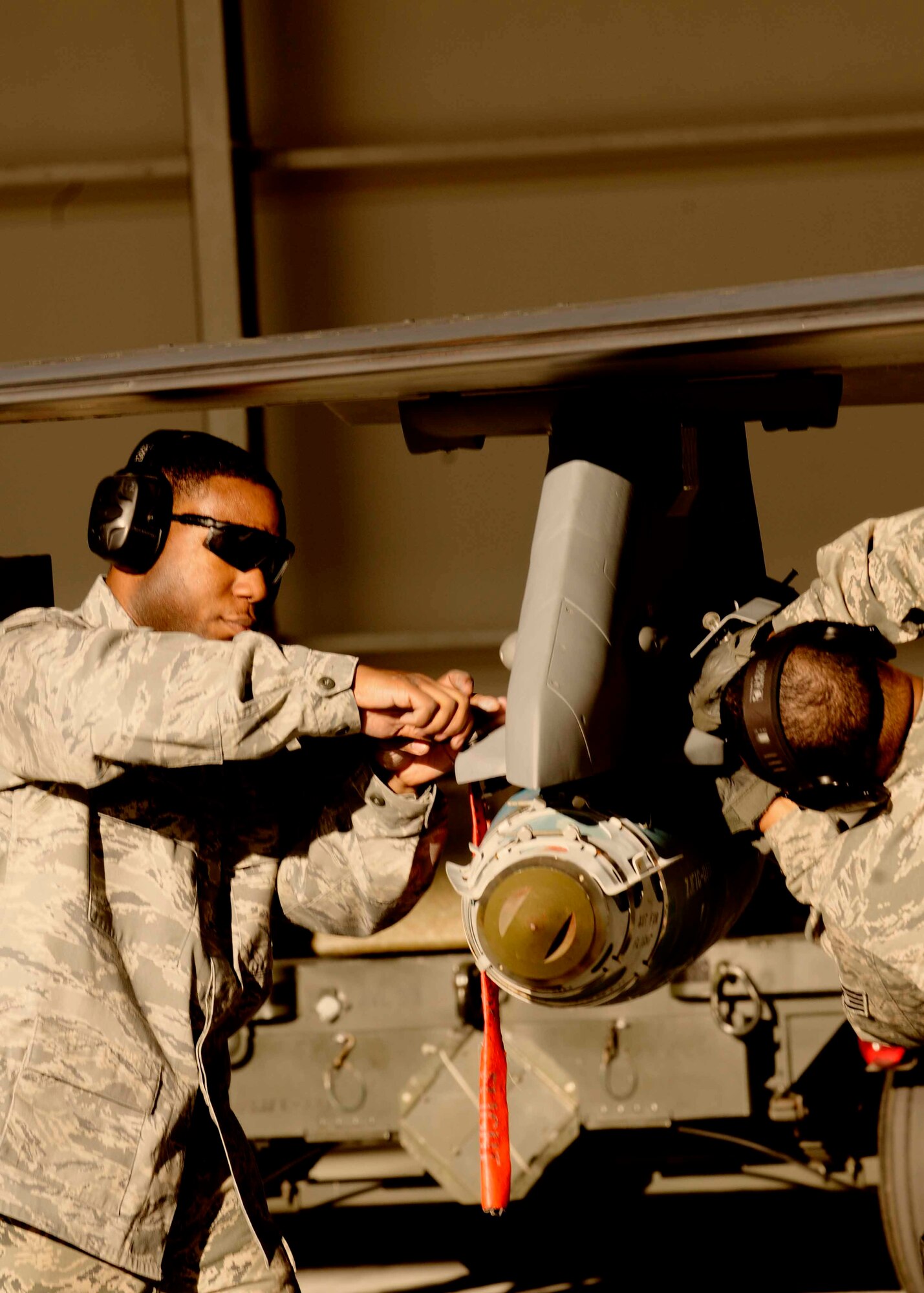 Senior Airman Julius Thomas, 31st Maintenance Group weapons load crew member, and Staff Sgt. Terelle Sayles, 31st Air Maintenance Squadron weapons load crew chief, secures a munition on an F-16 Fighting Falcon Jan.6 at Aviano Air Base, Italy. This was part of the fourth quarter loading competition in which the Airmen were judged on time and performance. (U.S. Air Force photo/Airman 1st Class Briana Jones)