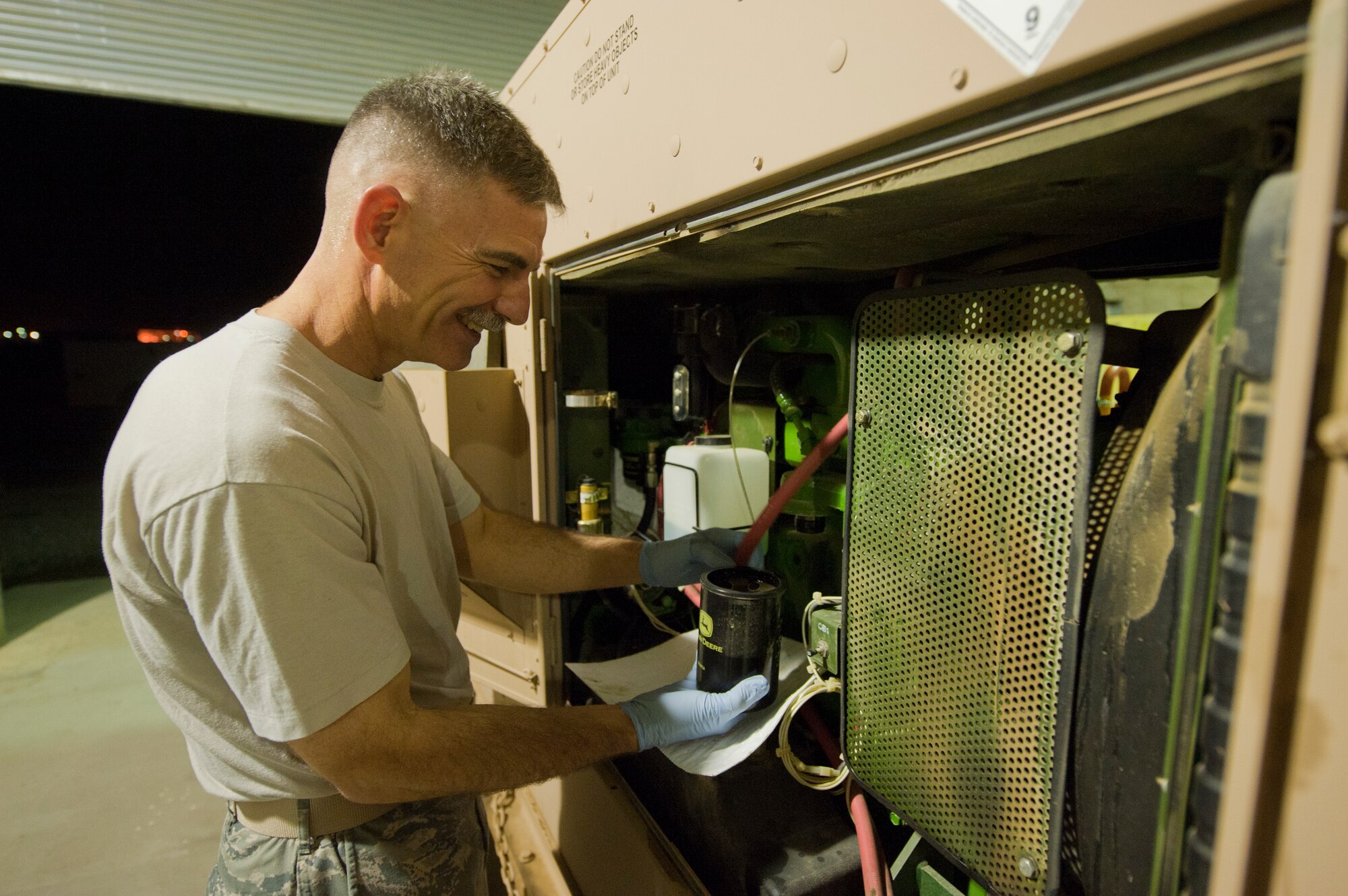 Chief Master Sgt. John Brinkley, 332nd Air Expeditionary Wing command chief, changes the oil on a power generator at an undisclosed location in Southwest Asia, Jan. 9, 2012. Brinkley started a program where he works alongside different flights and performs their tasks for the day. Members of the 332nd Expeditionary Civil Engineer Squadron power production flight briefed the command chief on their daily duties and performed oil changes on several generators during his visit. Brinkley is deployed from Scott Air Force Base, Ill. (U.S. Air Force photo by Staff Sgt. Joshua J. Garcia/Released)