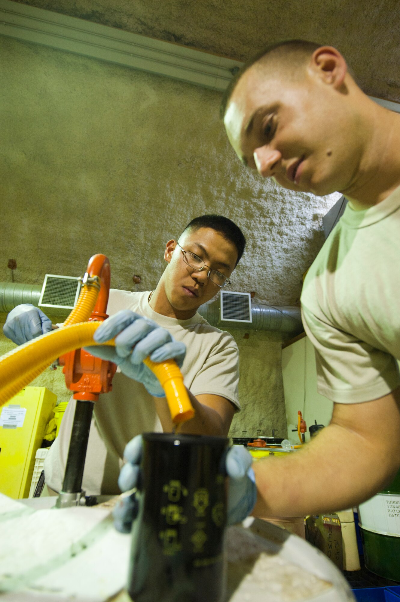 Senior Airman Ephesians Bagorio and Airman 1st Class Dominic Januzzi, 332nd ECES power production flight members, prepare an oil filter for an oil change during a preventive maintenance inspection on a generator at an undisclosed location in Southwest Asia, Jan. 9, 2012. Bagorio is deployed from Davis-Monthan Air Force Base, Ariz. and Januzzi is deployed from Shaw Air Force Base, S.C. (U.S. Air Force photo by Staff Sgt. Joshua J. Garcia/Released)