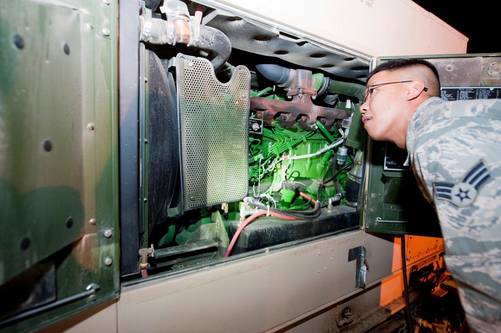 Senior Airman Ephesians Bagorio, 332nd Civil Engineer Squadron power production flight, performs a spot inspection on a generator at an undisclosed location in Southwest Asia, Jan. 9, 2012. The power production flight is in charge of maintaining all generators on the base. They perform inspections twice a day to ensure the generators are up to standard. Bagorio is deployed from Davis-Monthan Air Force Base, Ariz. (U.S. Air Force photo by Staff Sgt. Joshua J. Garcia/Released)