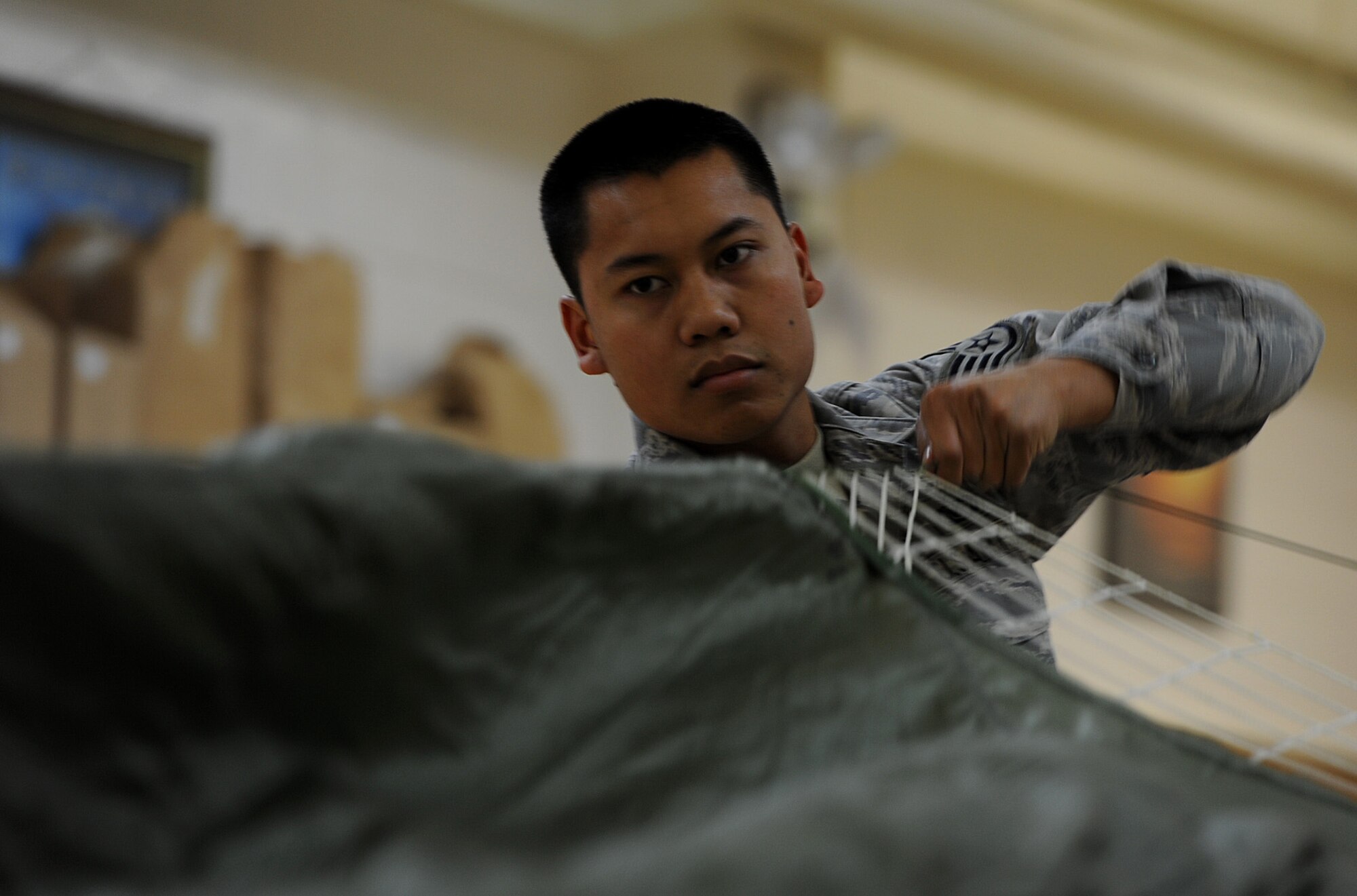 U.S. Air Force Staff Sgt. David Sivixay, 18th Operations Support Squadron air crew flight equipment craftsman, folds a MC-1 static line parachute during Beverly High 12-2, a local operational readiness exercise at Kadena Air Base, Japan, Jan 10, 2012. The LORE is an exercise that Kadena Airmen participate in to hone skills and keep them sharp in the event of real-world emergencies. (U.S. Air Force photo by Senior Airman Jarvie Z. Wallace)  
