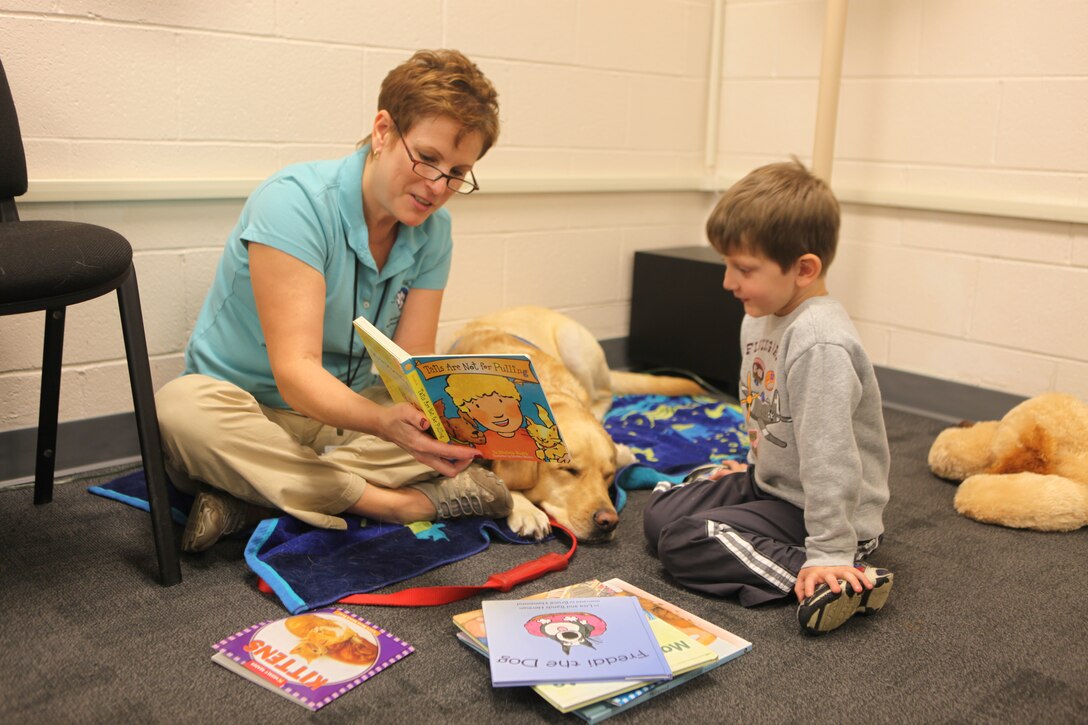 A participant of the Reading to Dogs event reads to a trained Coastal Carolina Pet Provided Therapy dog and its facilitator at the Harriotte B. Smith Library aboard Marine Corps Base Camp Lejeune, Jan. 11.